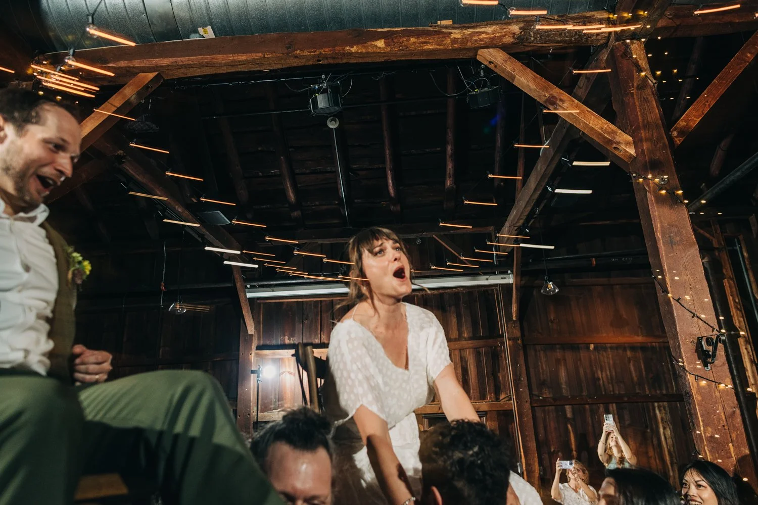 A bride and groom are lifted on chairs during their wedding reception at the red barn at hampshire college.