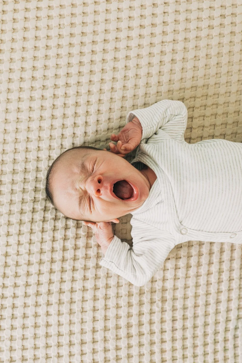 A newborn baby yawns during a newborn photography session in massachusetts