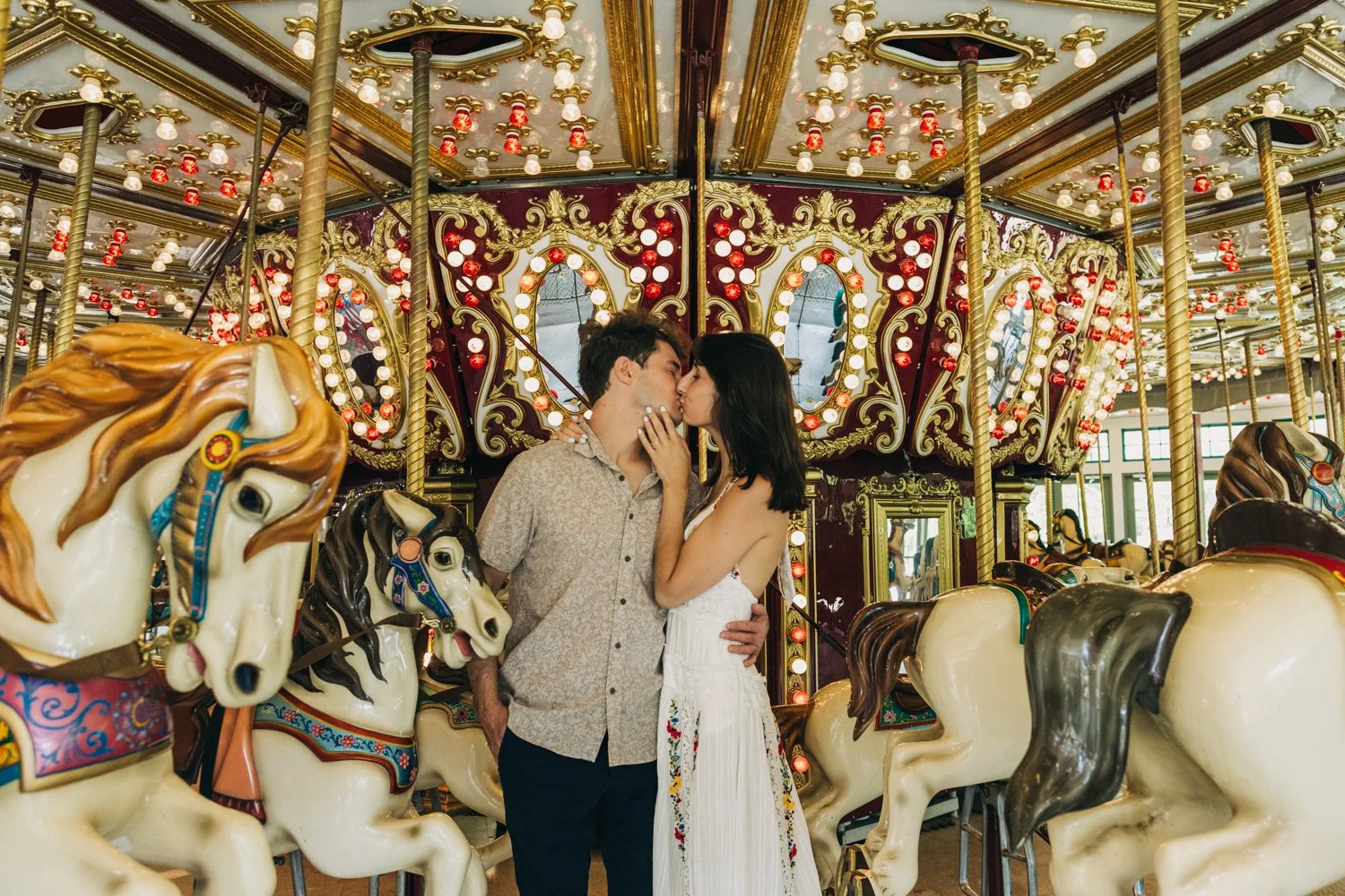 A couple rides the carousel at roger williams park in rhode island for their rhode island engagement photos.