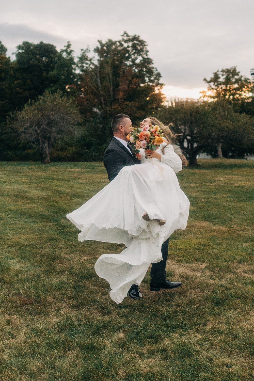 Candid wedding photo of a bride and groom joyfully running through a field during a wedding at western massachusetts wedding venue Gloriosa & Co in Ashfield, Massachusetts.