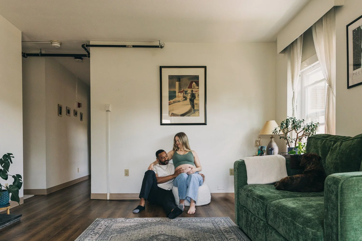 A couple sits together in their living room during a newborn photography session in western massachusetts.