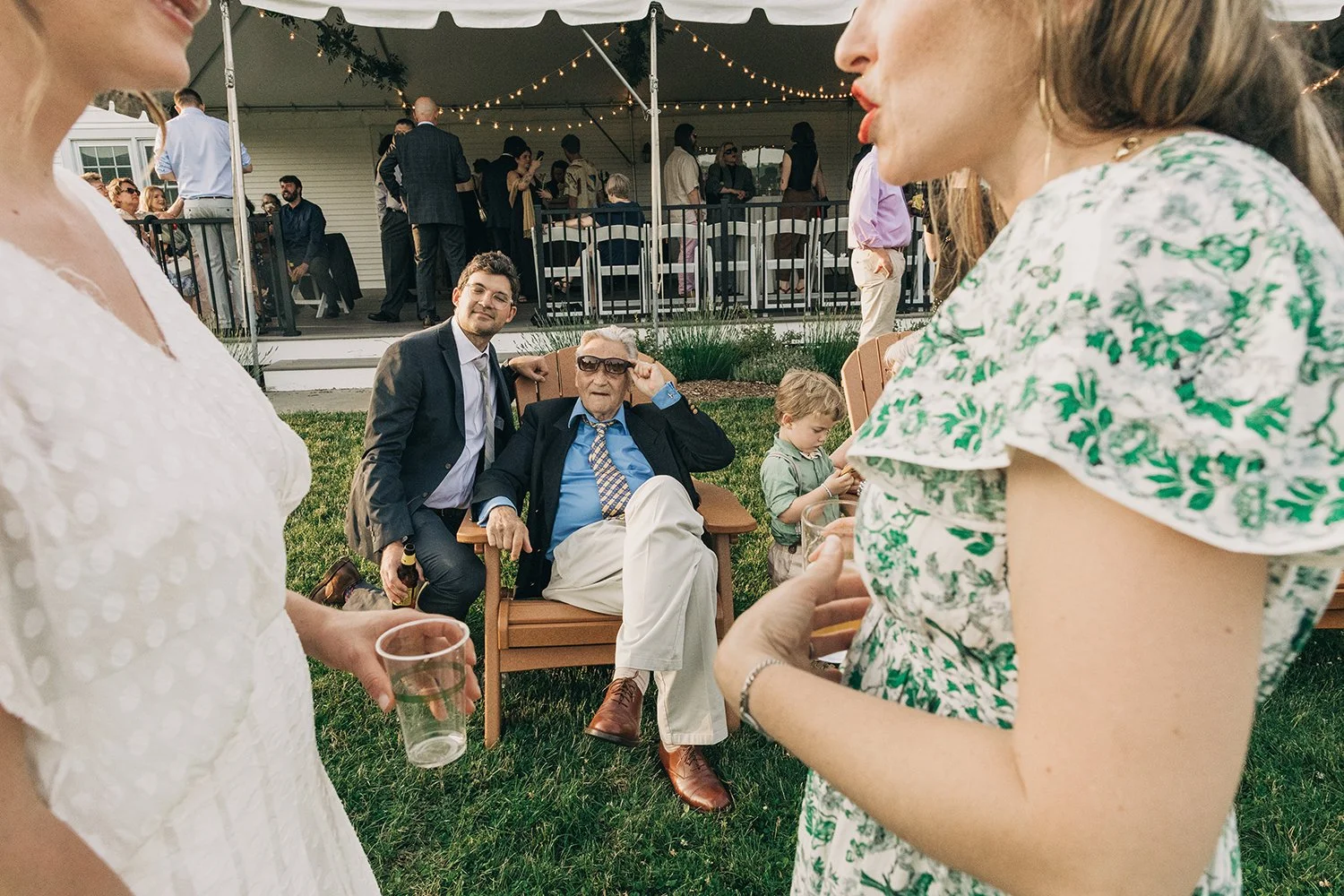 Guests look at a bride talk with her friend during social hour at a wedding at the red barn at hampshire college in amherst, massachusetts.