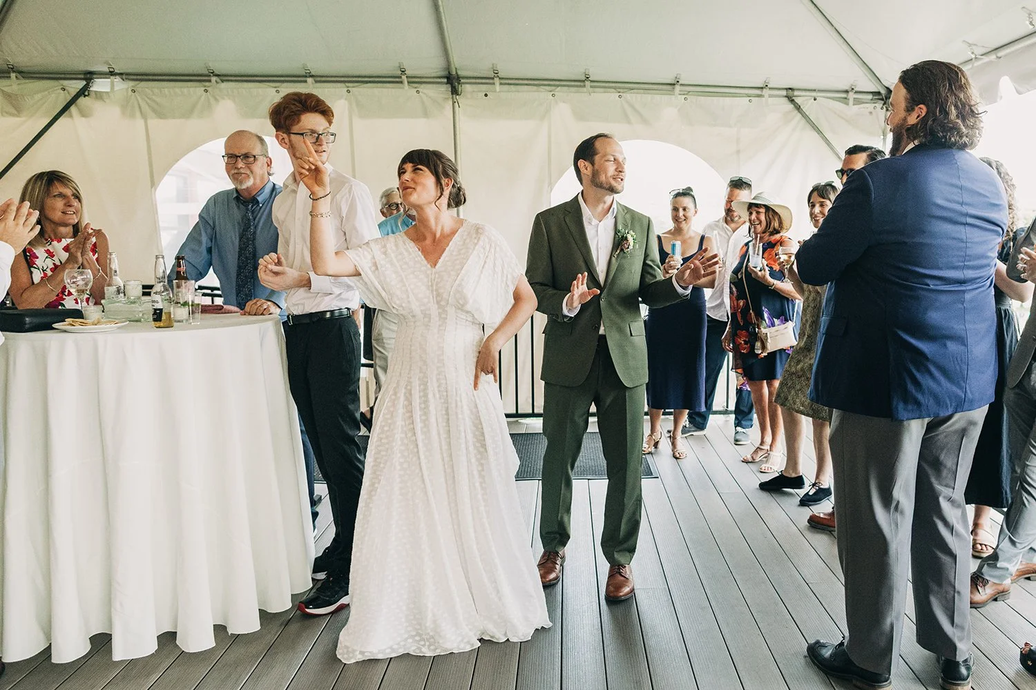 A bride and groom are welcomed into their cocktail hour by their guests during their wedding at the red barn at hampshire college in amherst, massachusetts