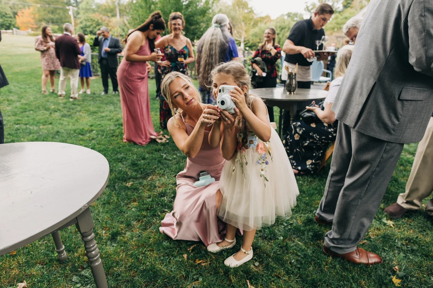 A girl takes a photo with a polaroid camera during a wedding at western massachusetts wedding venue Gloriosa & Co in Ashfield, Massachusetts.