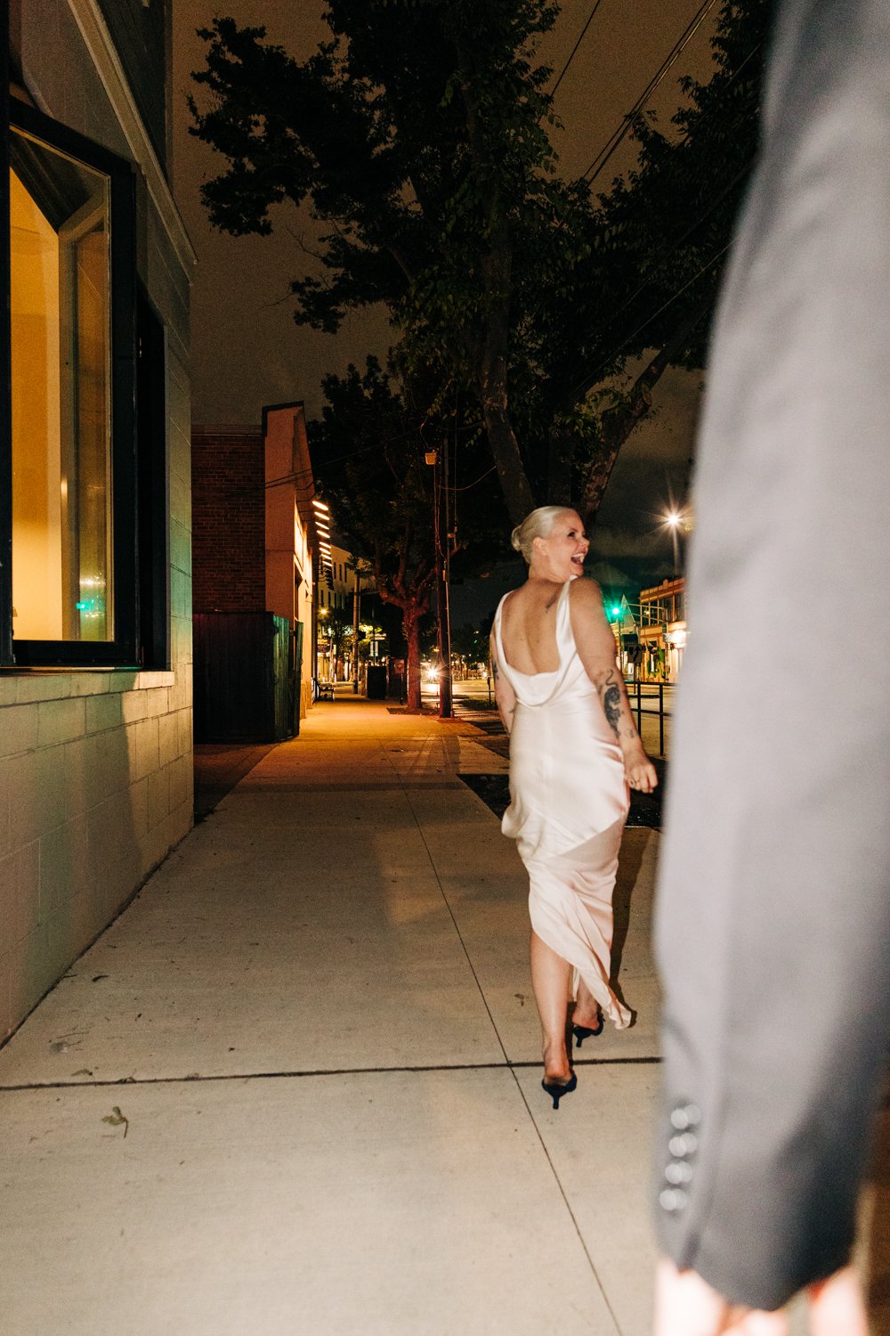 A bride walks joyfully down the sidewalk out side of Juliet in Somerville during her small wedding.