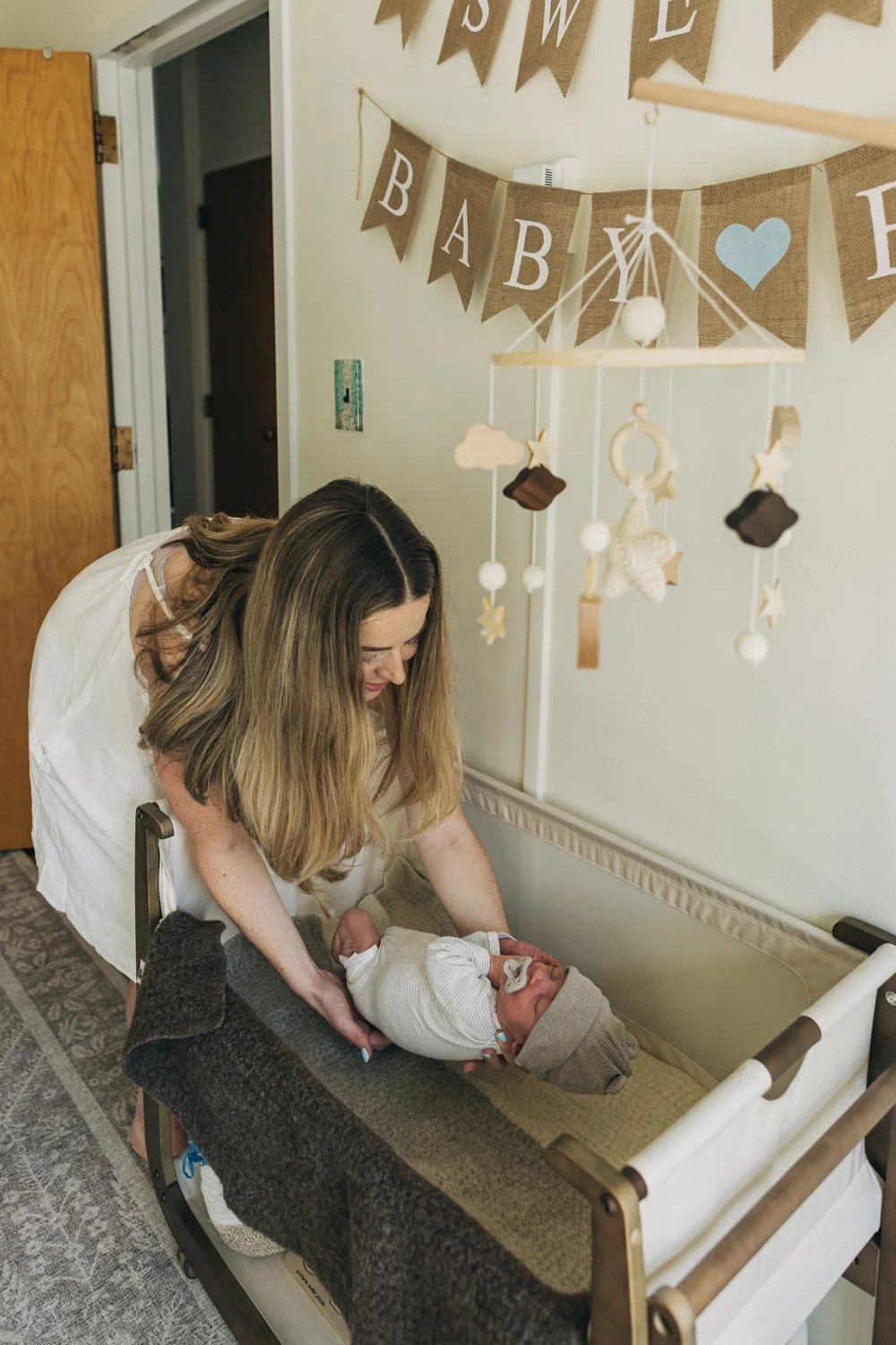 A mother places her newborn baby into a crib during a newborn photography session in western massachusetts.