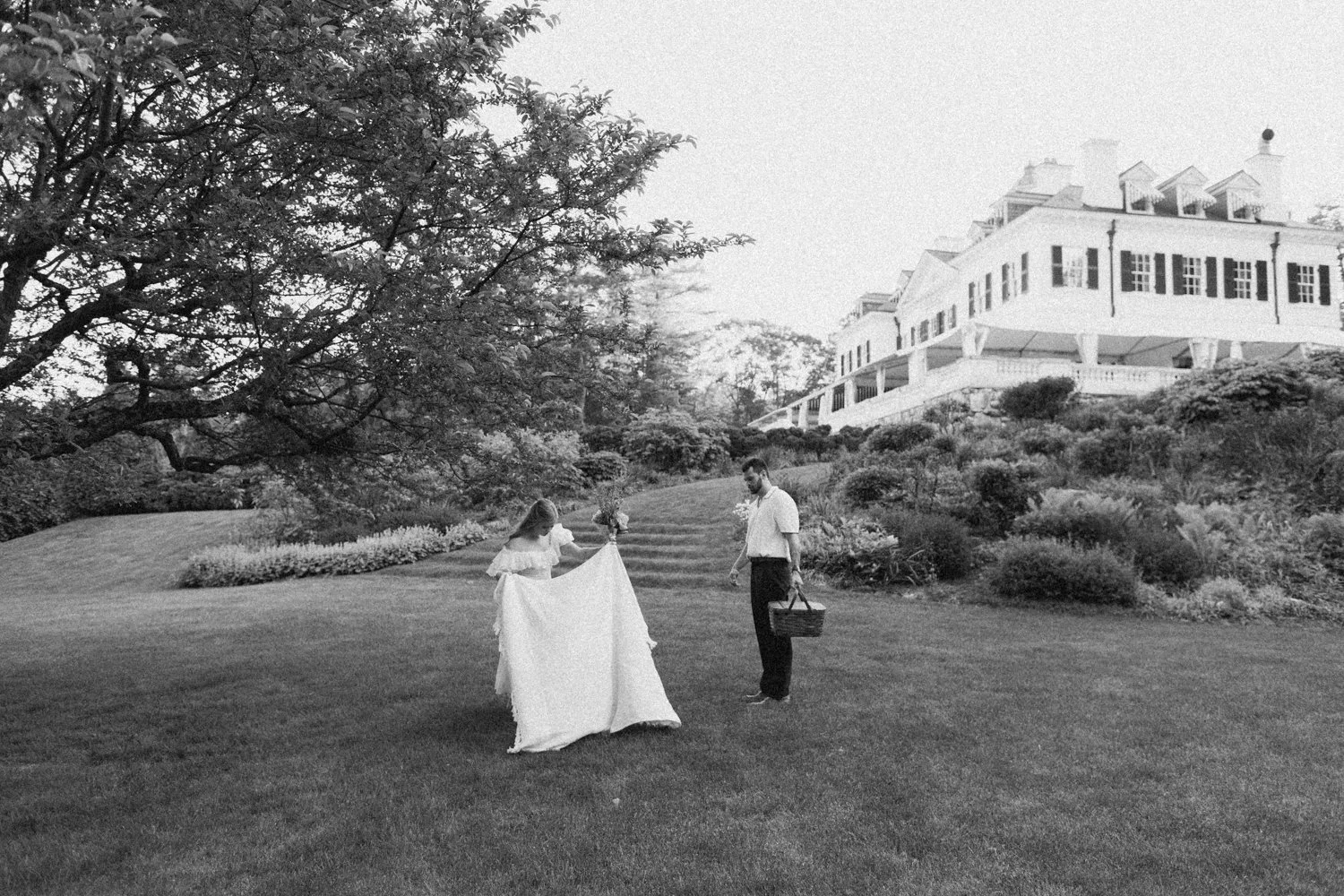 A couple enjoys a picnic while exploring the grounds at their engagement sessionat the Mount, Edith Wharton's Home, in Lenox, Massachusetts.