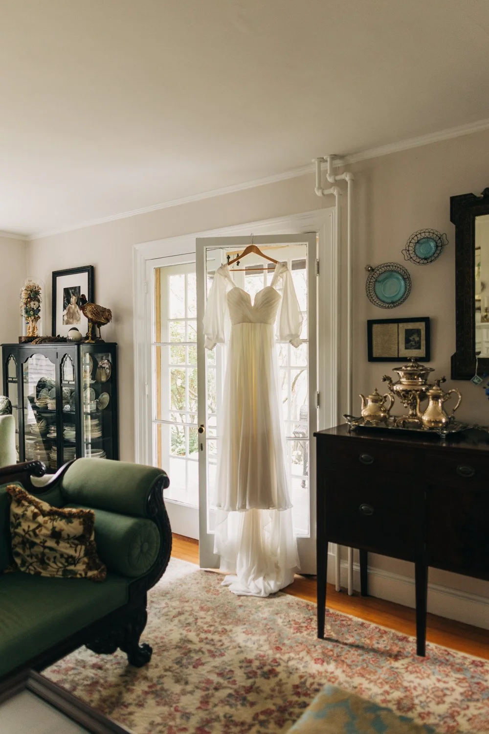 A wedding dress is hung on a french door during a wedding at western massachusetts wedding venue Gloriosa & Co in Ashfield, Massachusetts.