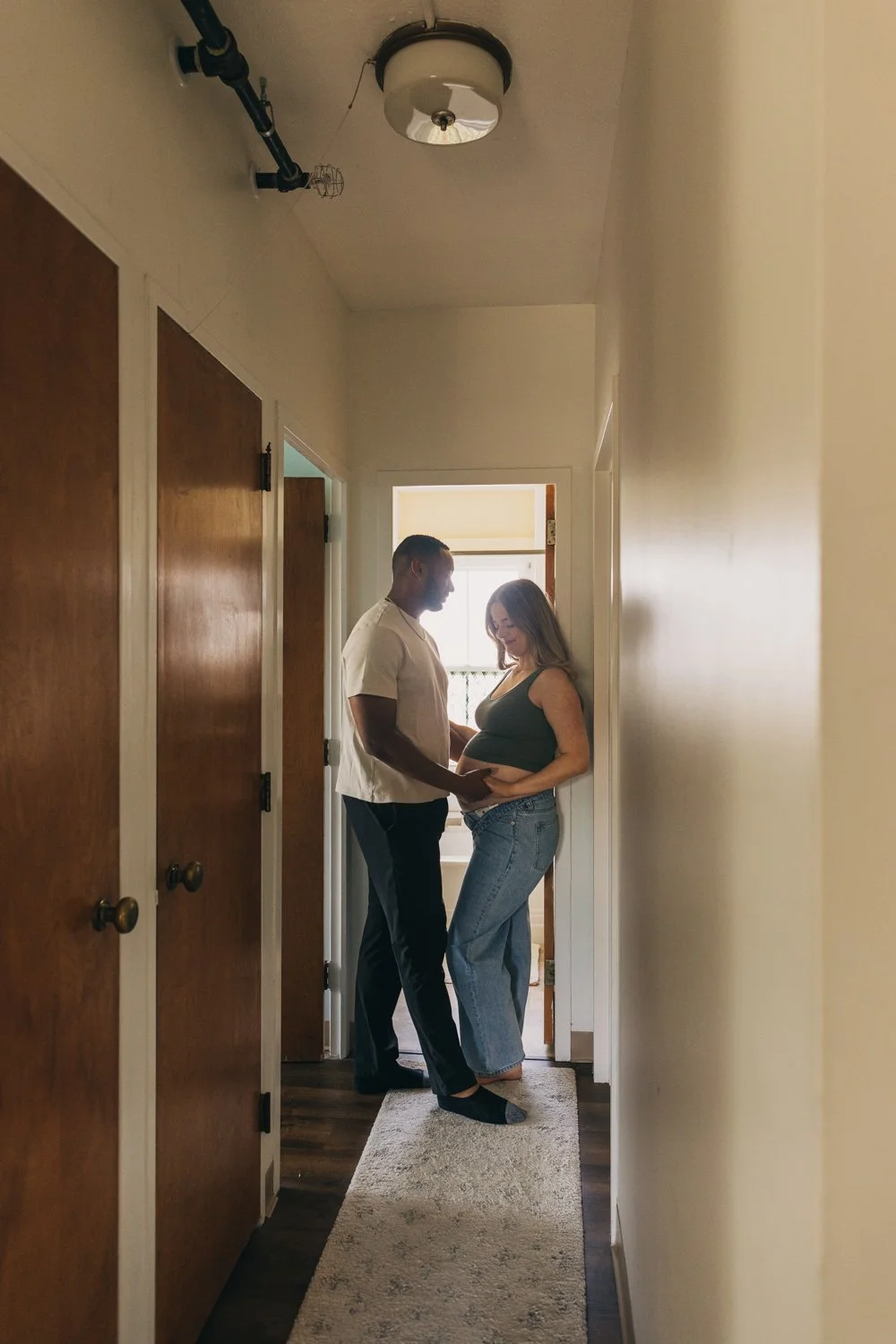 Candid portrait of a couple standing in the hallway of their apartment during their maternity photo session in western massachusetts.