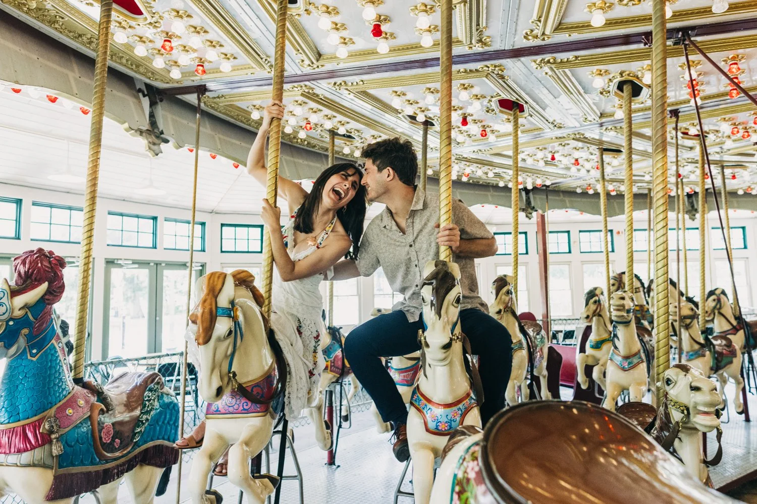 A couple rides the carousel at roger williams park in rhode island for their rhode island engagement photos.