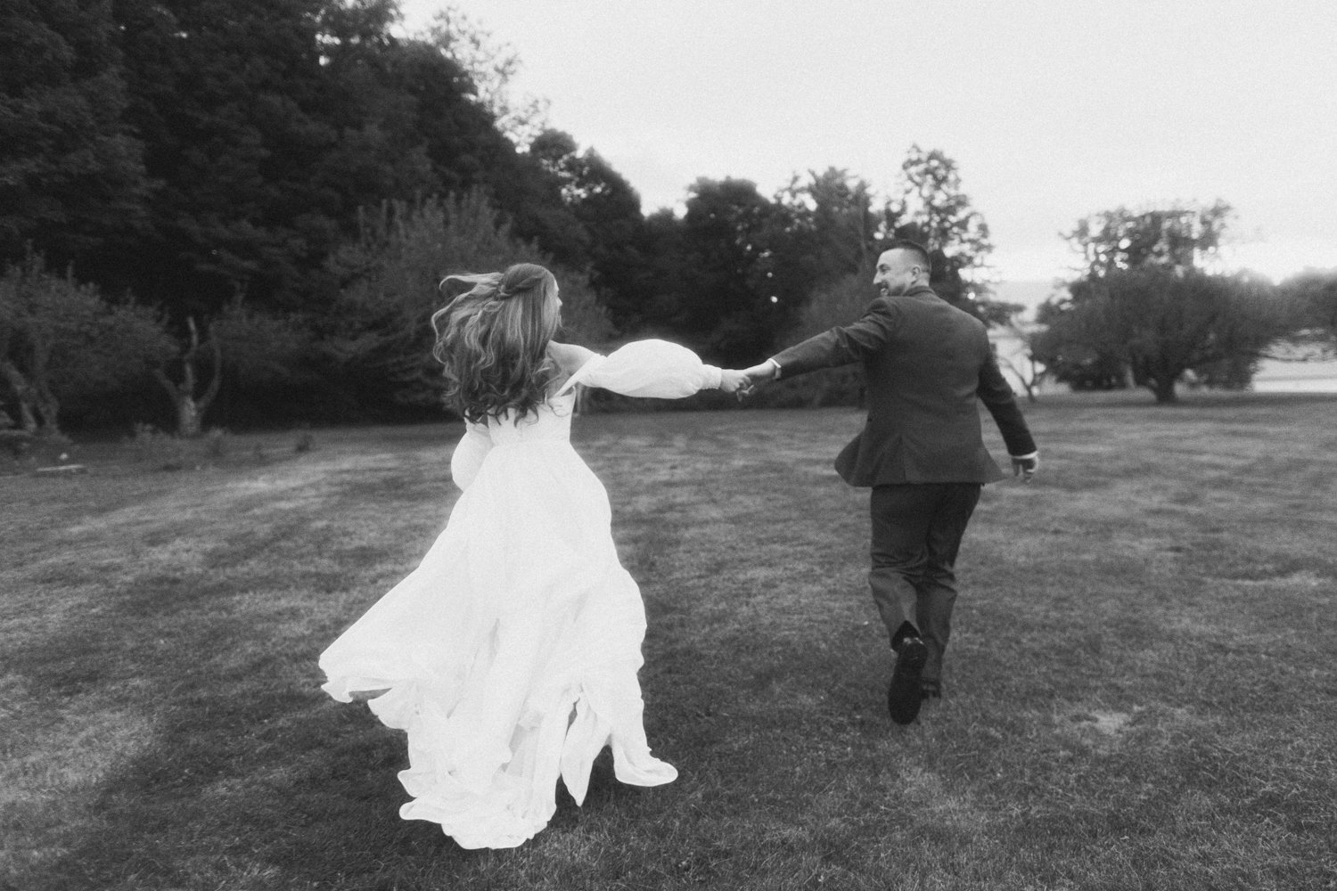 A bride and groom hold hands and run through a field during a wedding at western massachusetts wedding venue Gloriosa & Co in Ashfield, Massachusetts.