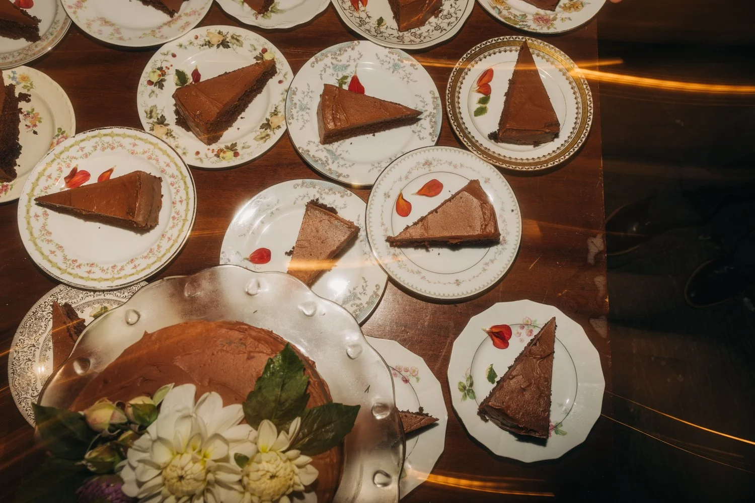 Flourless chocolate cake is plated on a collection of vintage plates at a wedding at western massachusetts wedding venue gloriosa& co in ashfield, massachusetts