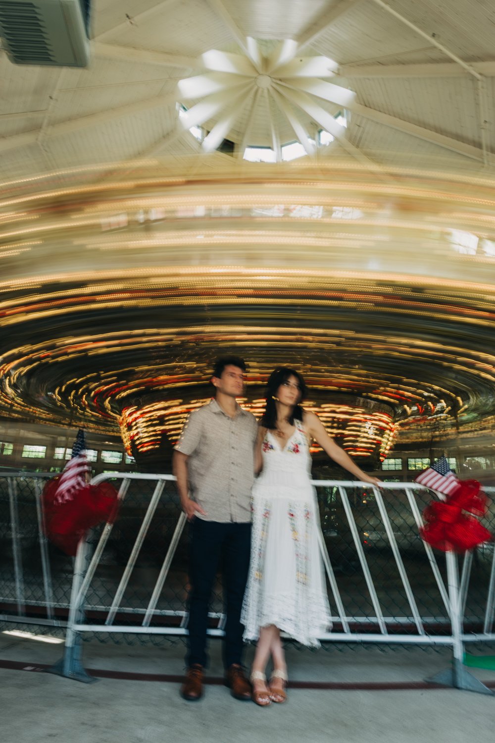 A couple rides the carousel at roger williams park in rhode island for their rhode island engagement photos.