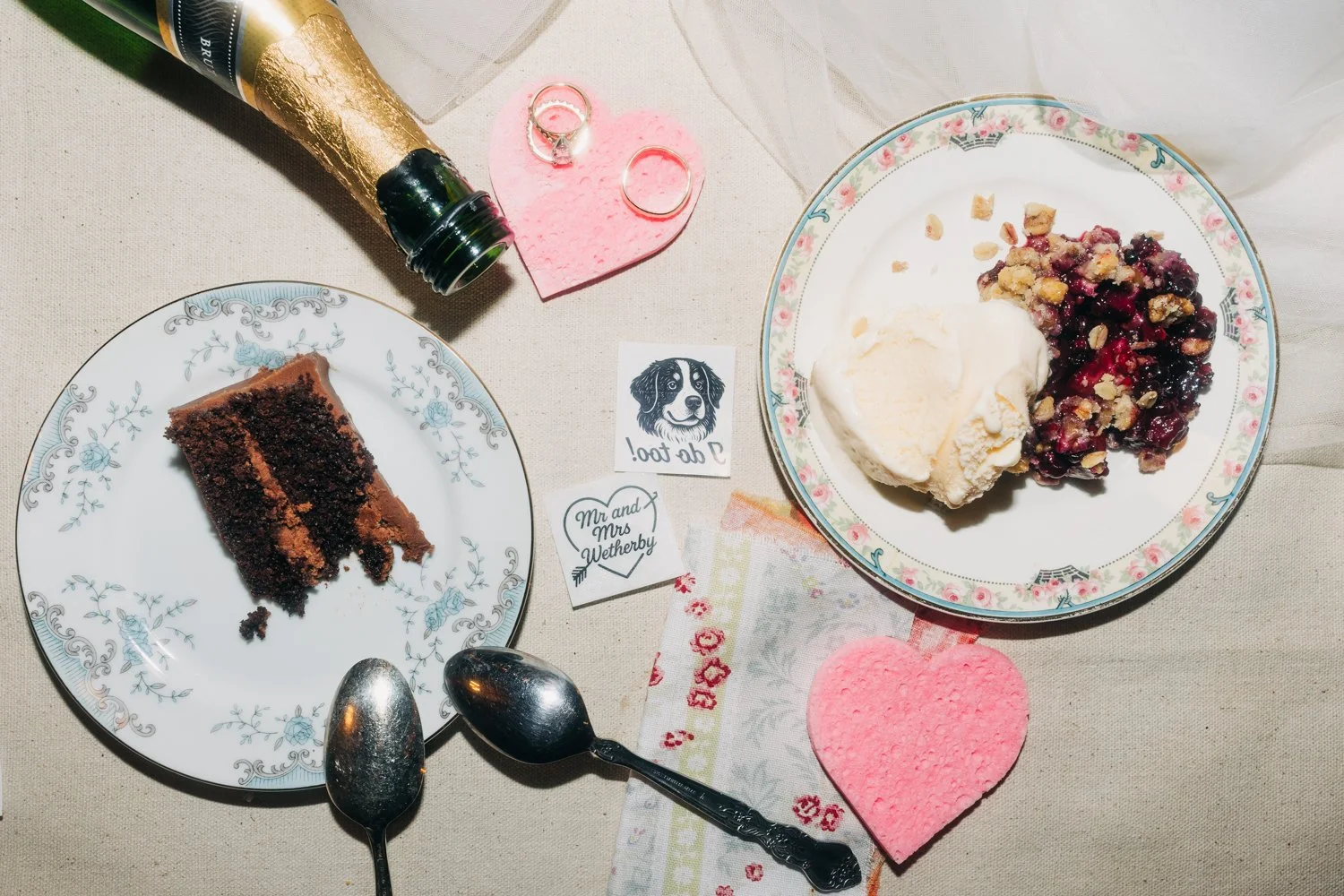 A detail photo of cake, rings, tattoos, champagne, and pie, at the end of the night during a wedding at western massachusetts wedding venue gloriosa & co in ashfield, massachusetts.