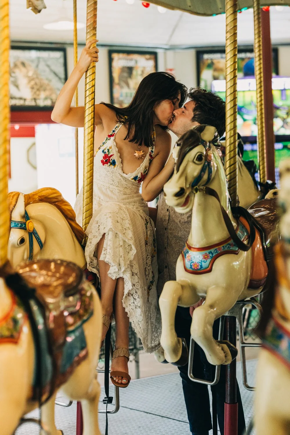 A couple rides the carousel at roger williams park in rhode island for their rhode island engagement photos.