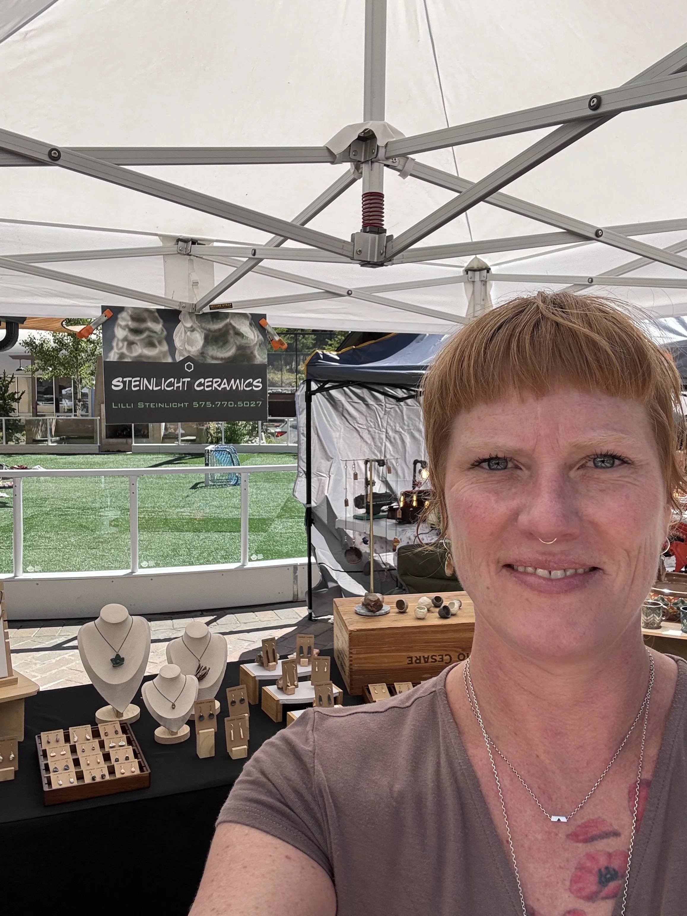 Lilli Steinlicht at an outdoor art market in Taos Ski Valley, with ceramic jewelry displayed.