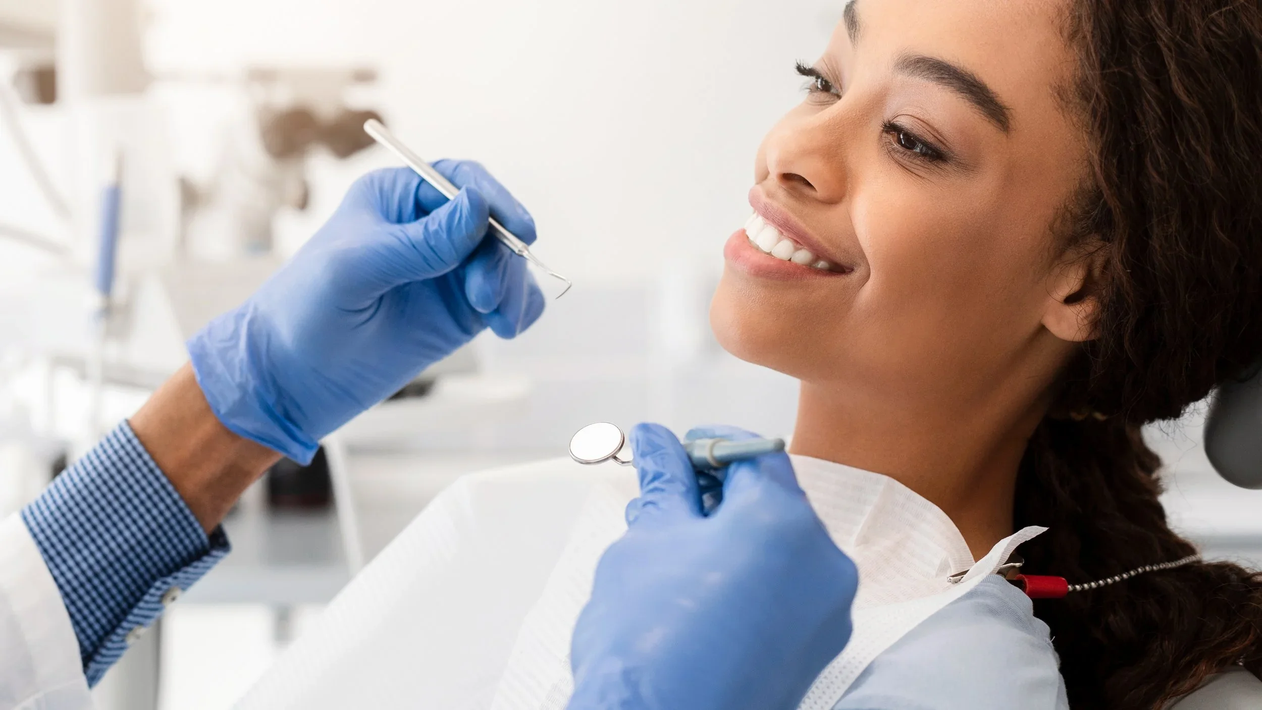 Patient receiving dental veneer consultation with dentist holding tools in Boulder cosmetic dentistry office.