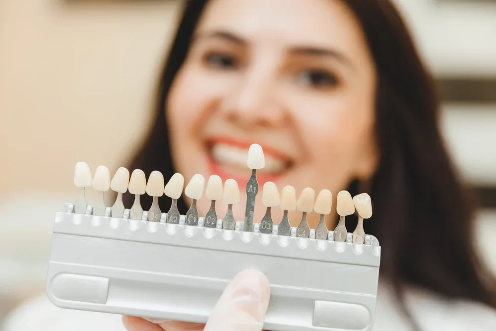 Patient holding dental shade guide to select perfect color match for custom veneers in Boulder.