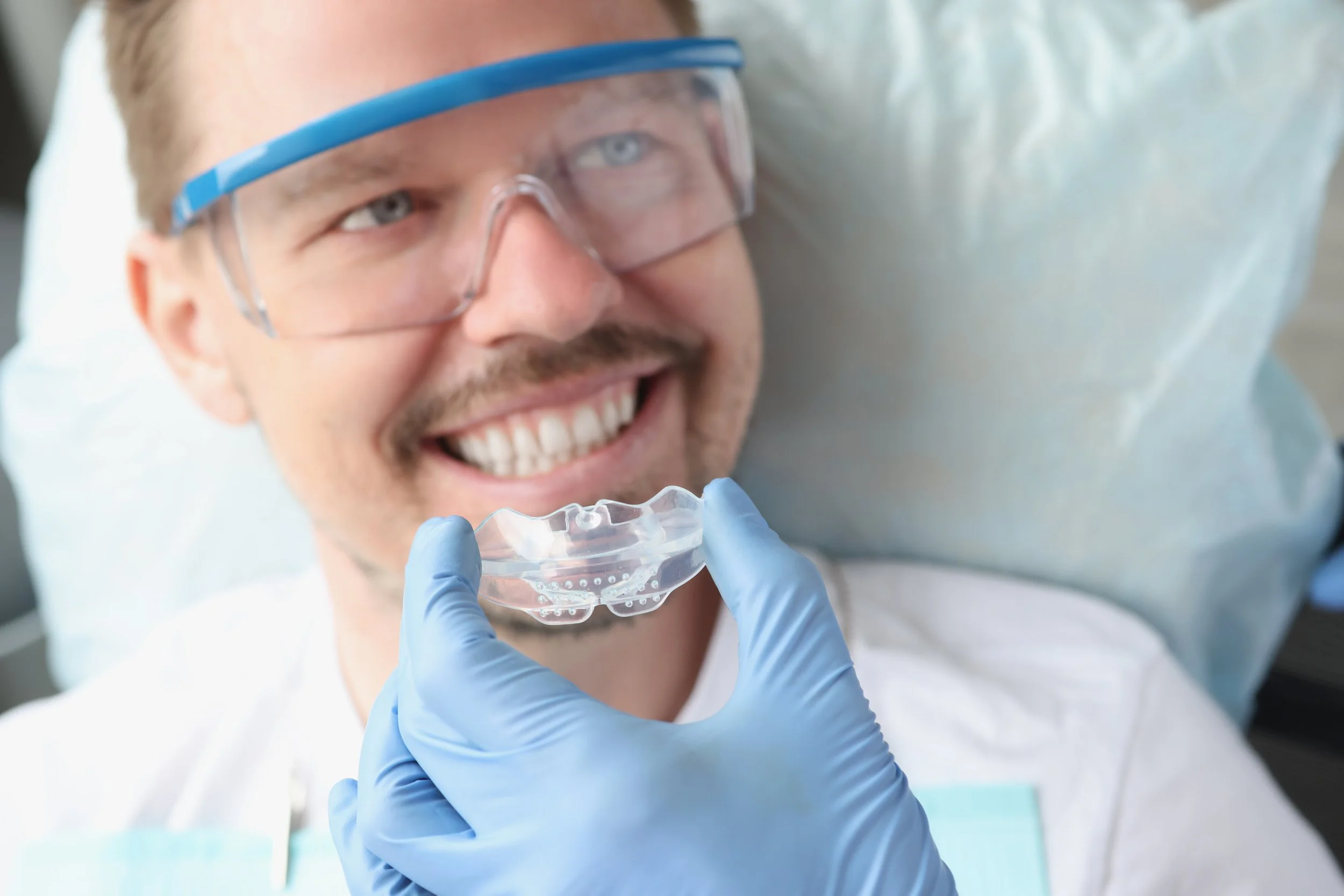 Patient and dentist examining transparent clear aligner together during orthodontic treatment consultation session.