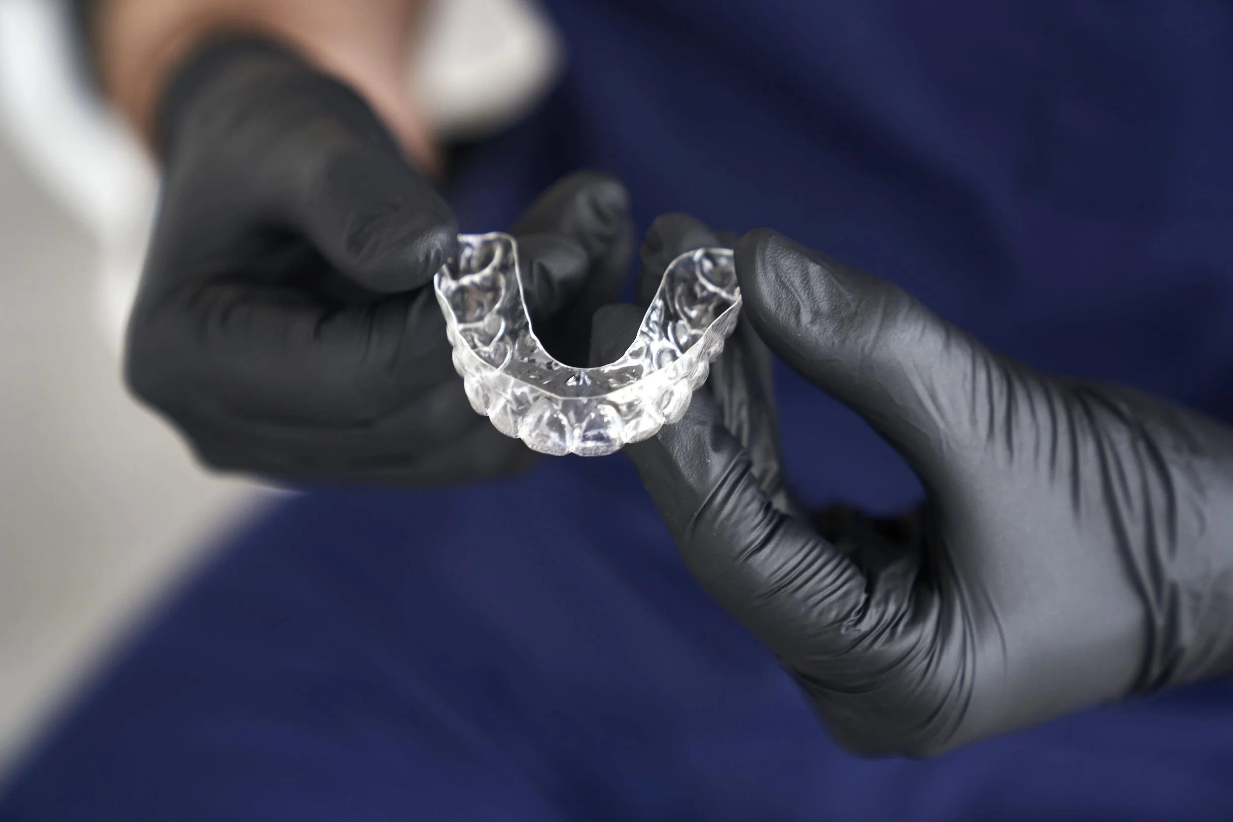 Clear orthodontic aligner resting in purple protective case on white surface with clock and plants
