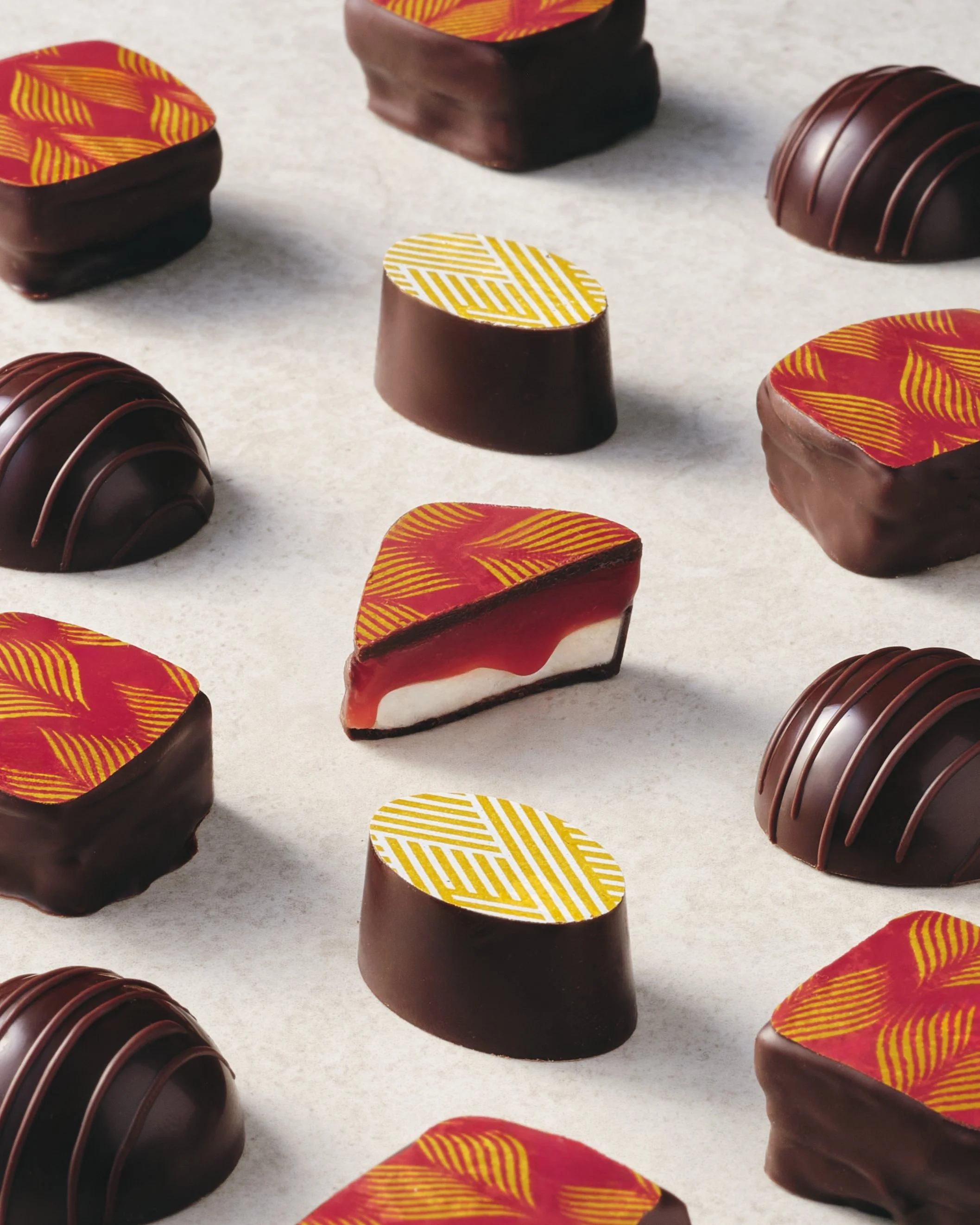 Assorted chocolate confections with colorful, patterned toppers on a white surface.