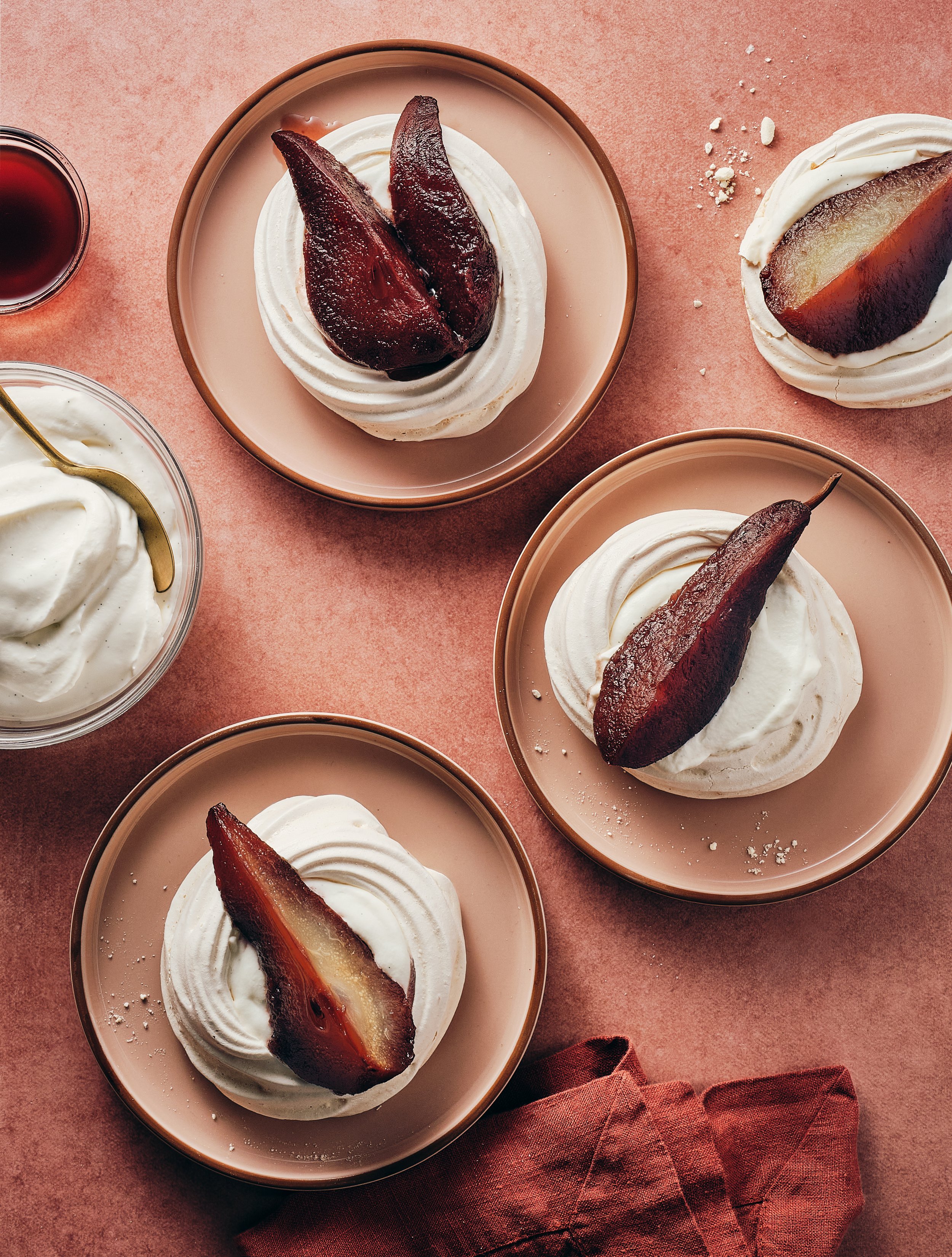 Dessert cups with whipped cream and roasted pear slices on pink background.