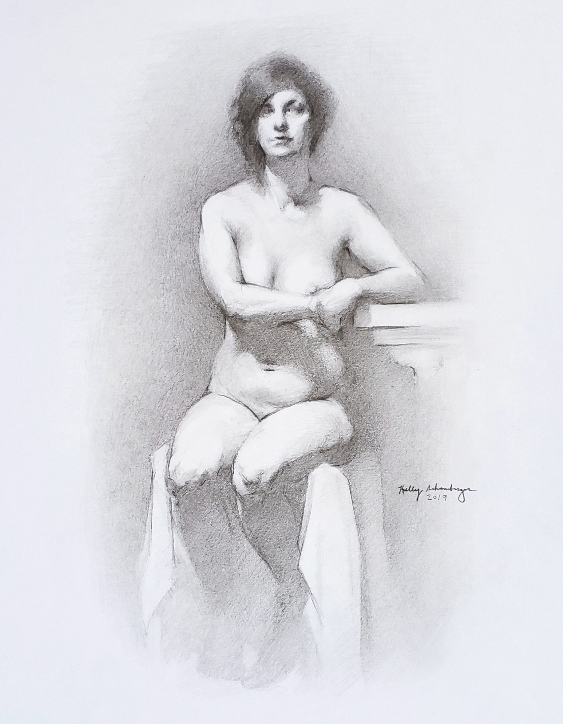 A pencil sketch of a nude woman sitting on a stool with an arm resting on a table, with short hair and a serious expression, signed by Kelly Schamberger in 2019.