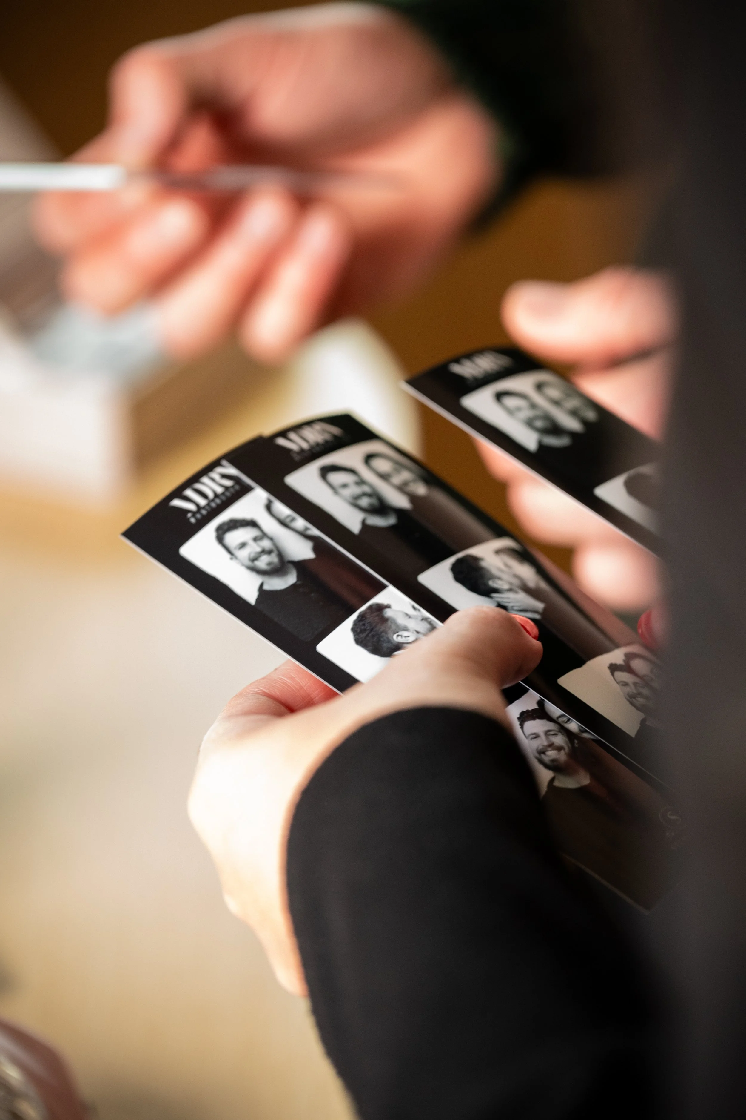 Wedding guest holding black-and-white photo strips from MDRN's vintage photo booth at a Stonefields wedding near Ottawa