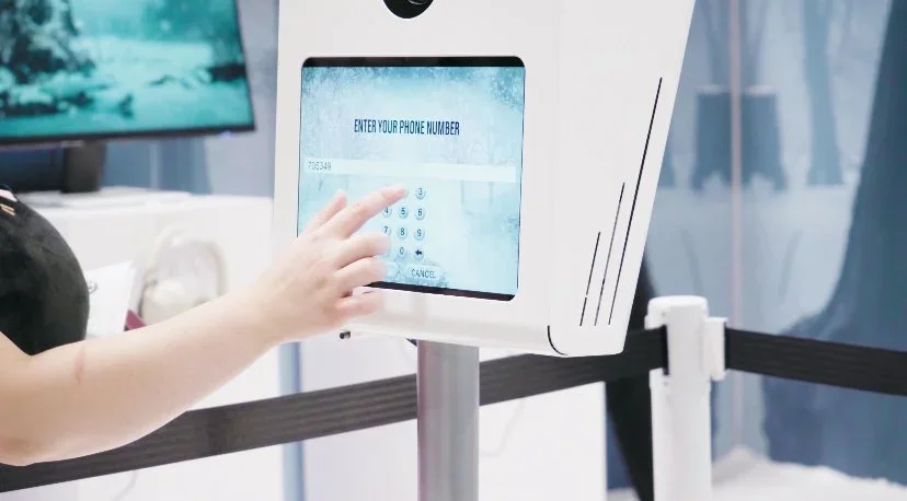 Guest entering phone number on interactive photo booth for data capture during experiential brand activation.