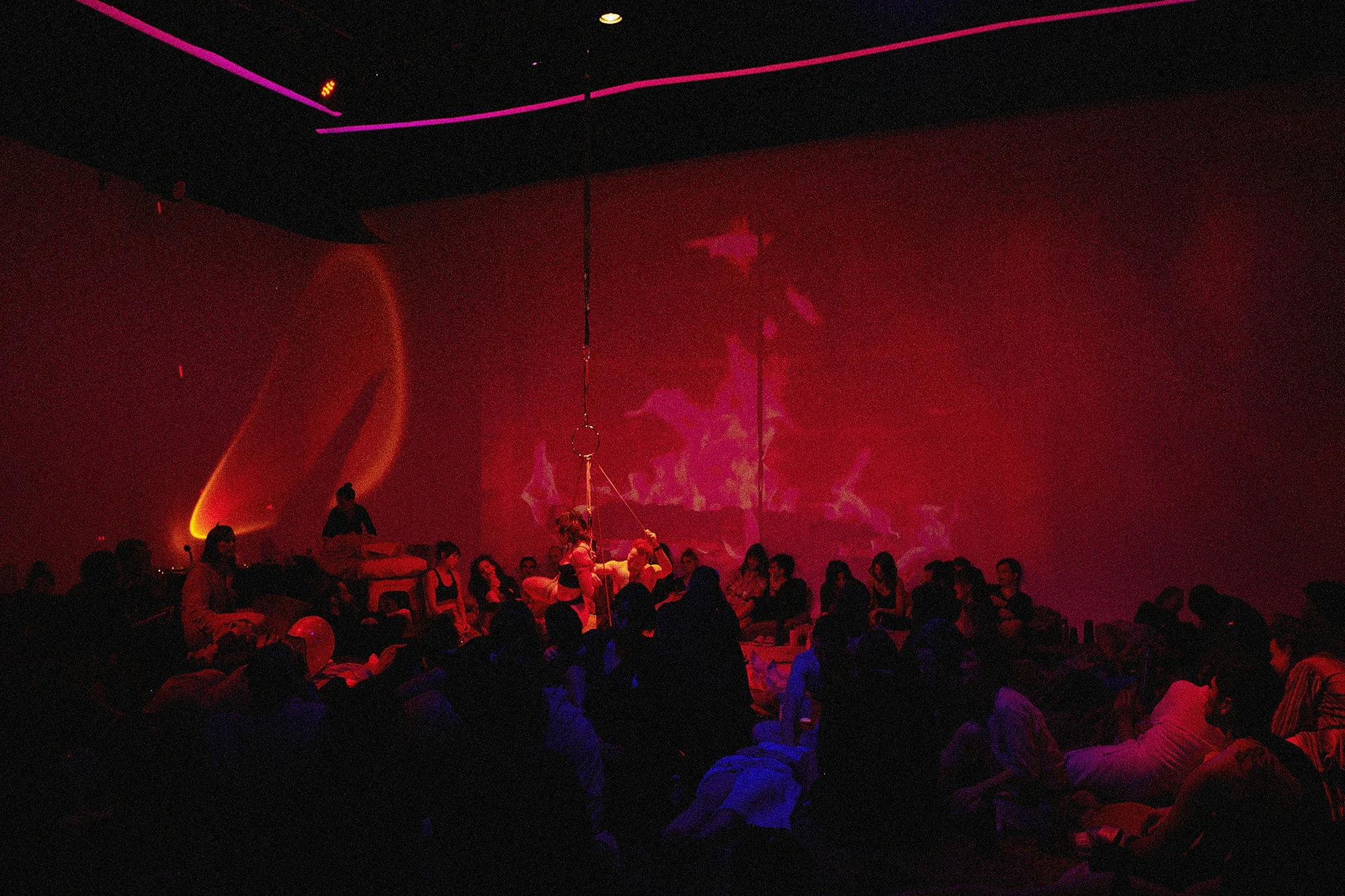 Dan Carabas and Dorcara performing a contemporary Shibari rope art piece in a large festival space with a live audience surrounding them.