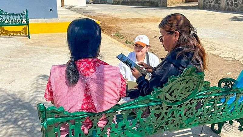 Women sitting on bench with another person sitting on the ground