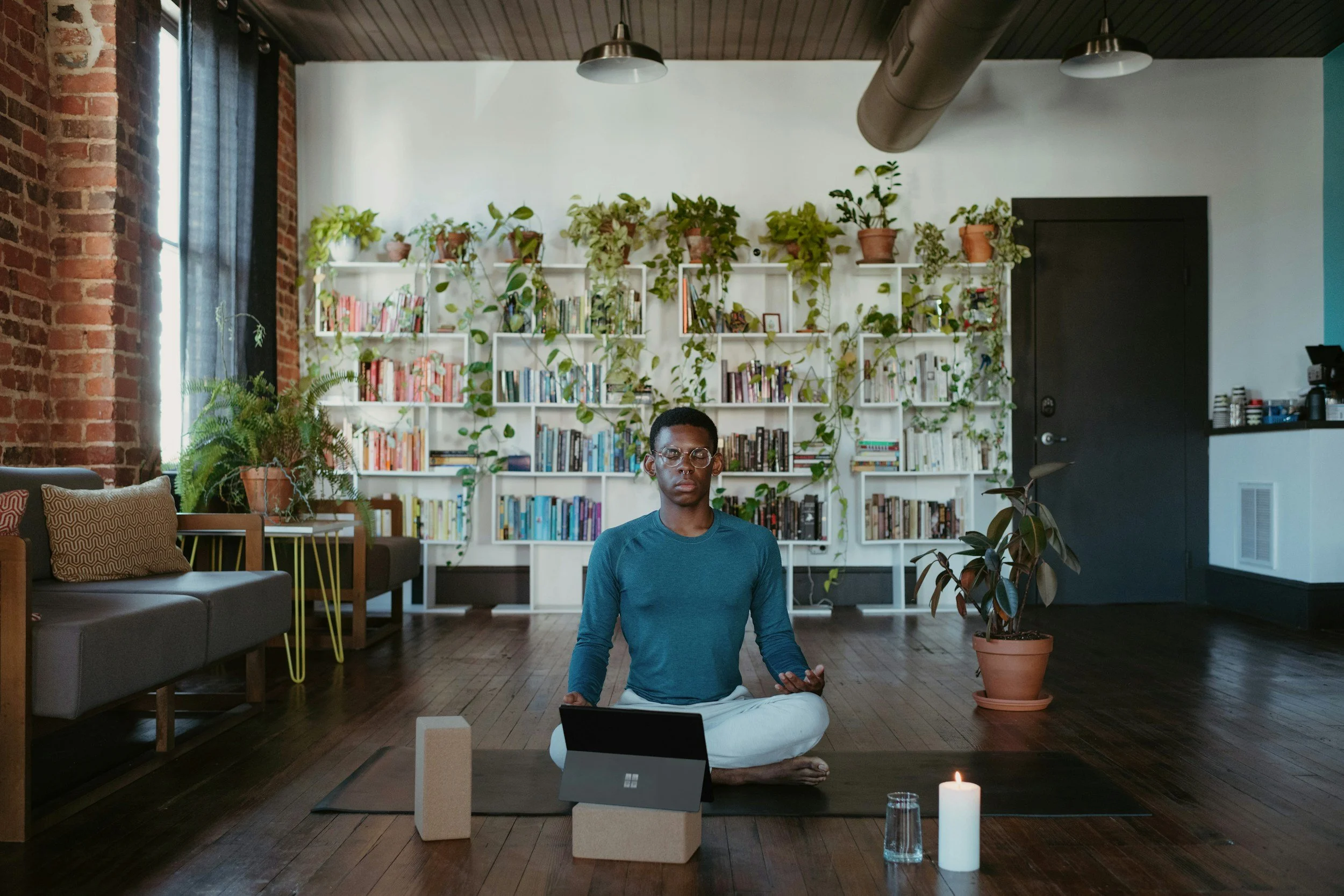 Male-presenting, person of color meditating at home.