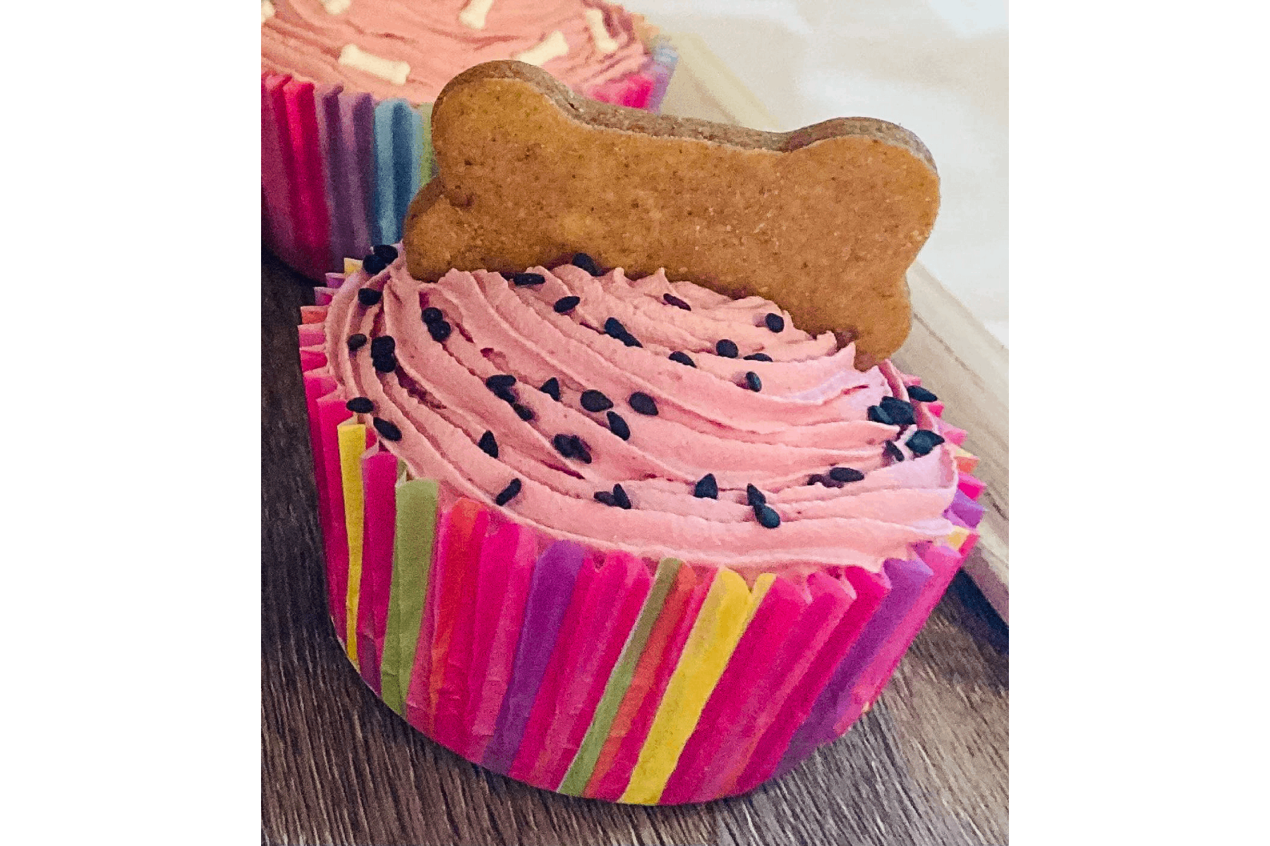 Pup cake in pink with bone topper and sesame seeds.