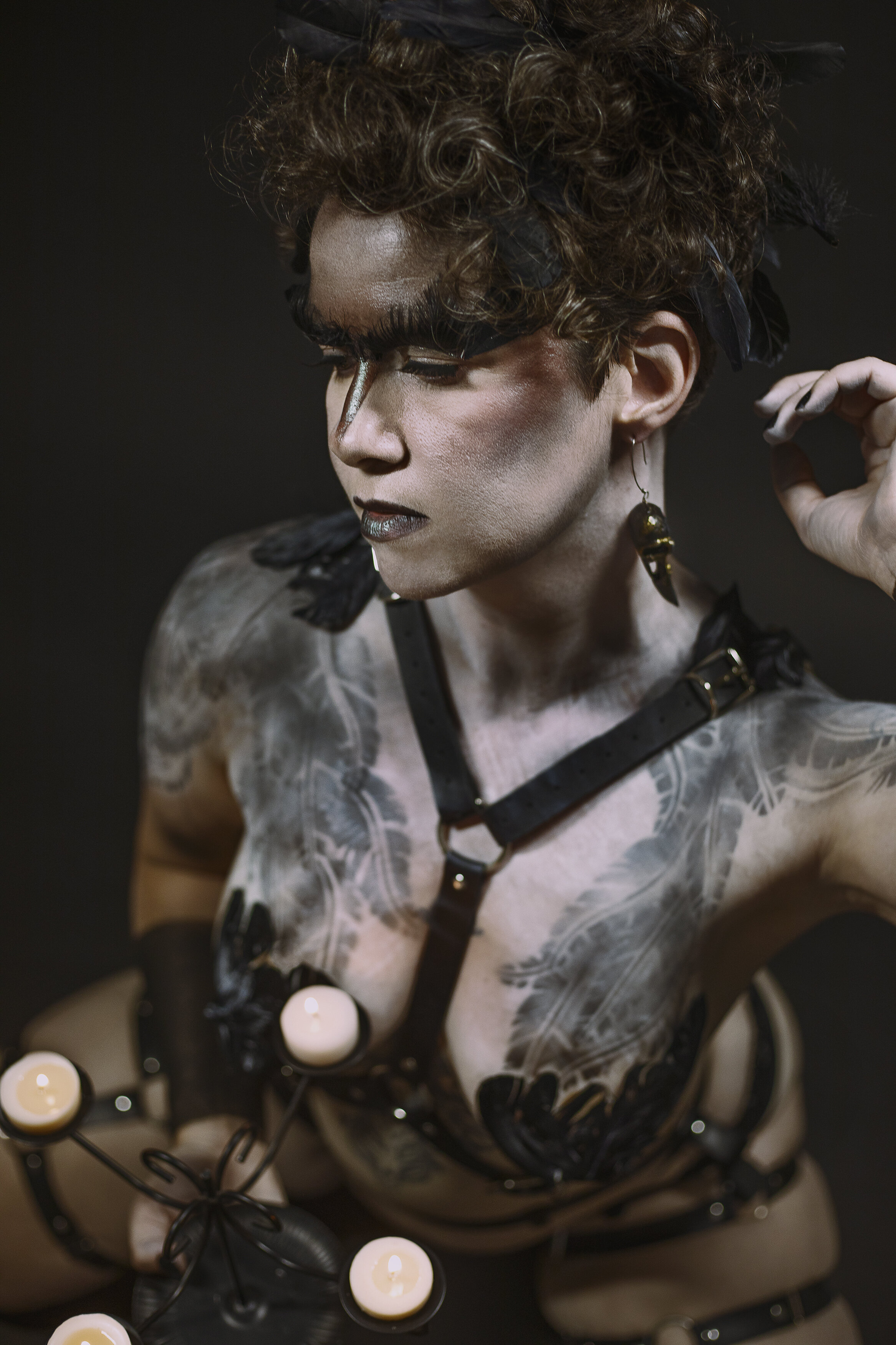 fantasy raven boudoir edmonton photography studio woman with bodypaint feathers harness and lit candelabra