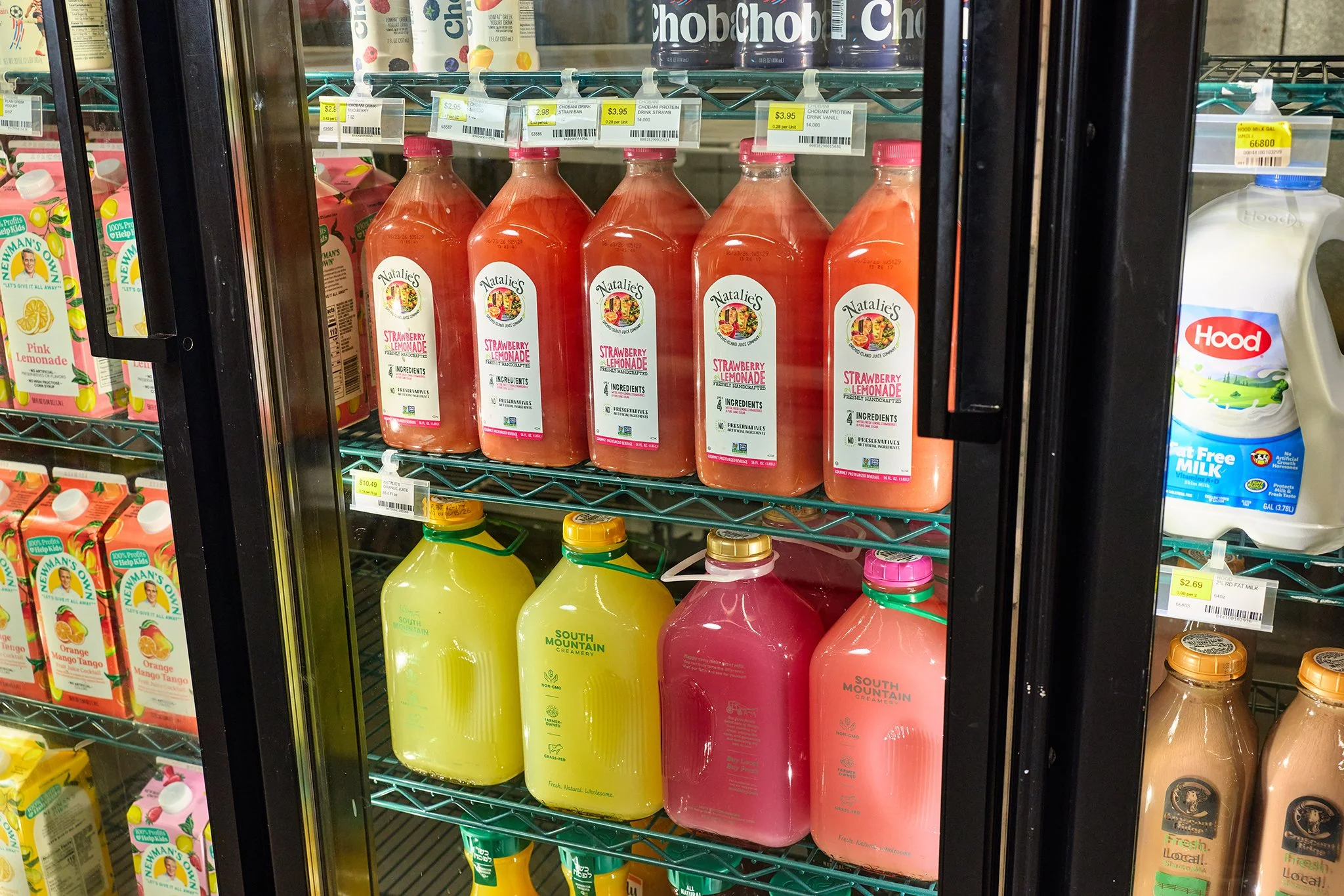 Refrigerator door with bottles of Natalie’s Strawberry Lemonade and South Mountain Creamery beverages inside.