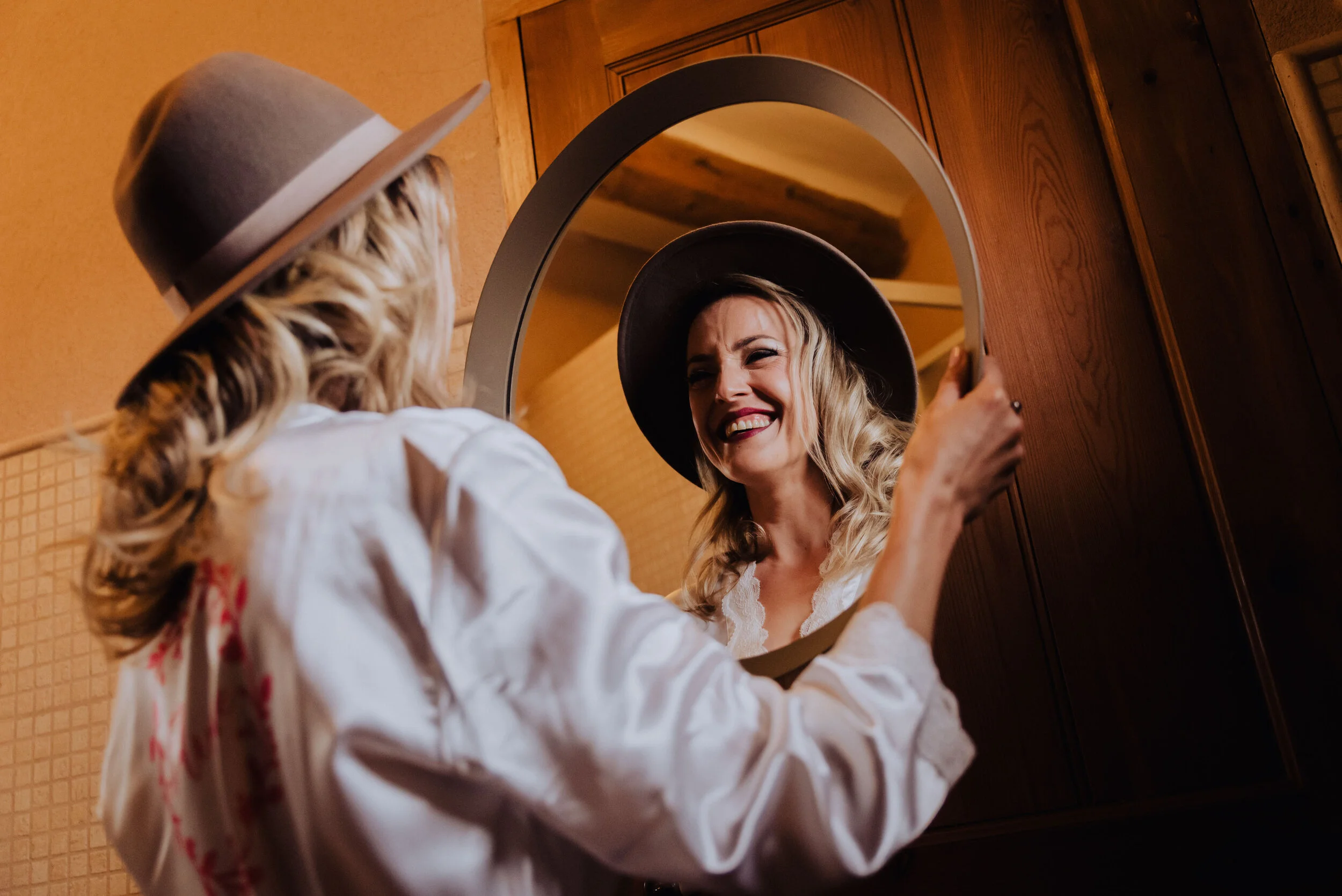 Mujer sonriente con sombrero reflejada en un espejo. Fotógrafo de bodas en Sant Celoni (Barcelona y Catalunya)