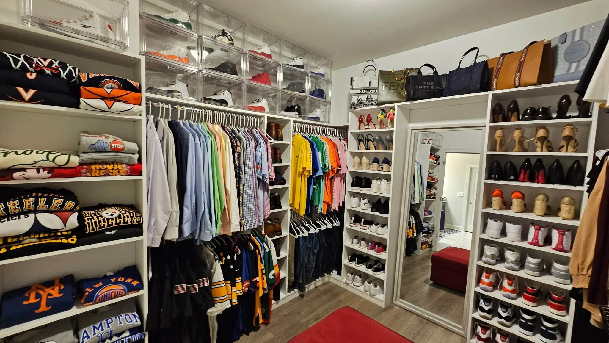 A walk-in closet with shelves of sneakers, hanging clothes, and handbags in a tidy space