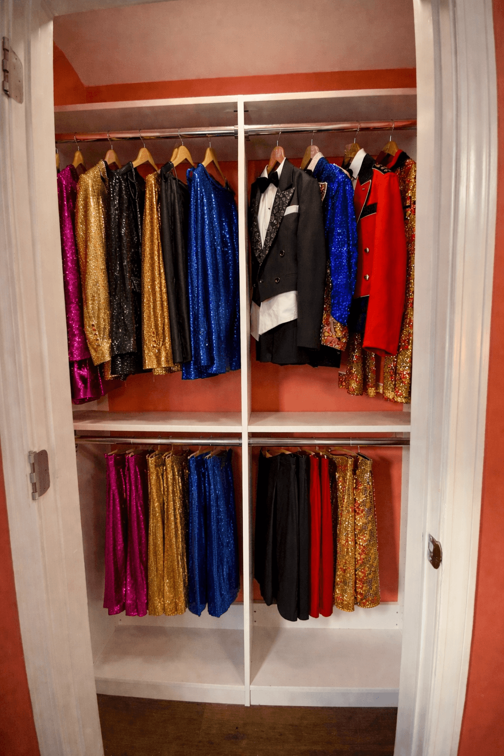 Closet with colorful sequined jackets and suits, including gold, black, blue, red, and floral patterns, hung on wooden hangers.