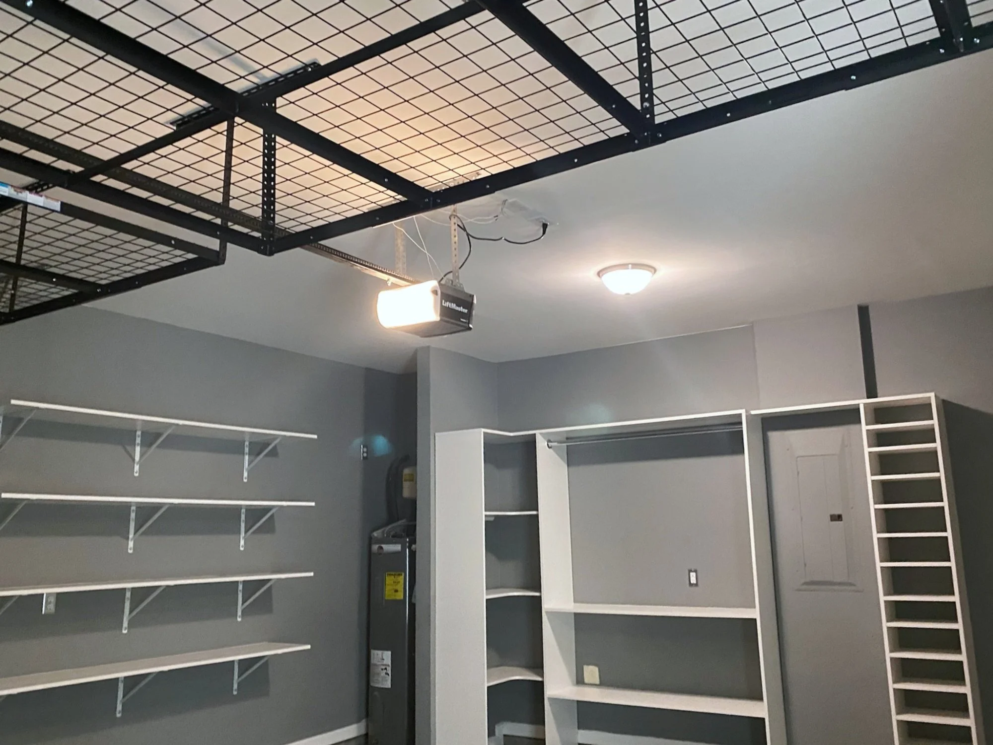 Empty retail store with black metal and glass shelving units, bright ceiling lights, and an overhead LED sign that says 'LiftMaster'.
