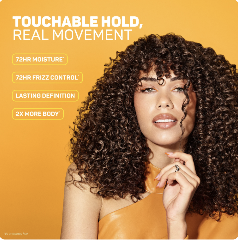 A woman with curly hair touching her chin against an orange background promoting hair care benefits.