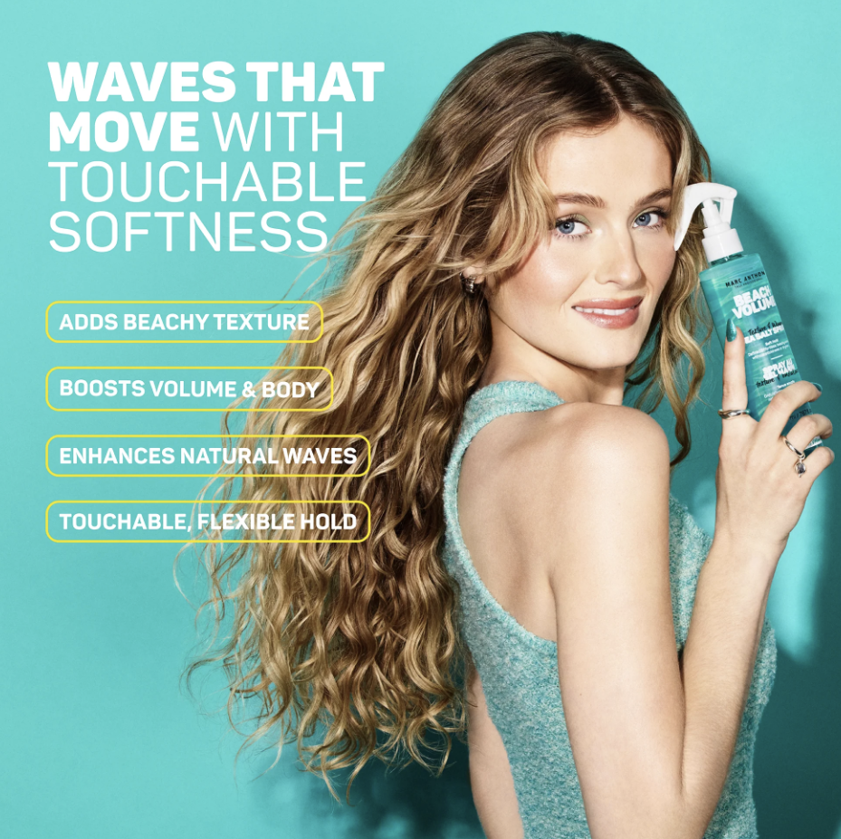 A woman with long, curly hair holding a spray bottle of beach wave styling product, smiling at the camera against a teal background, with text promoting the product's benefits.
