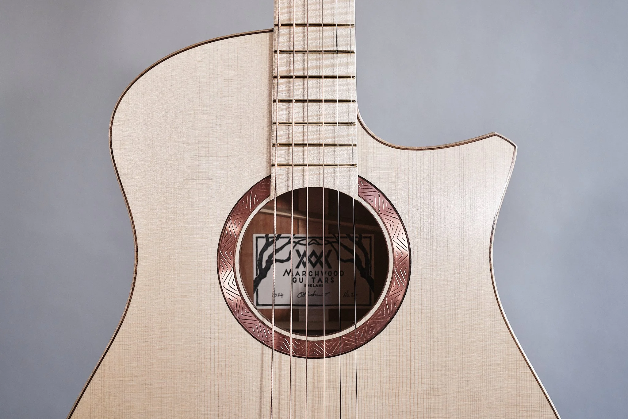 2025 String Break Show Guitar. OM 12 fret cutaway in Swiss spruce and English apple, with flamed maple fingerboard, bridge, binding and head plate, walnut purfling. Hand engraved copper rosette. 