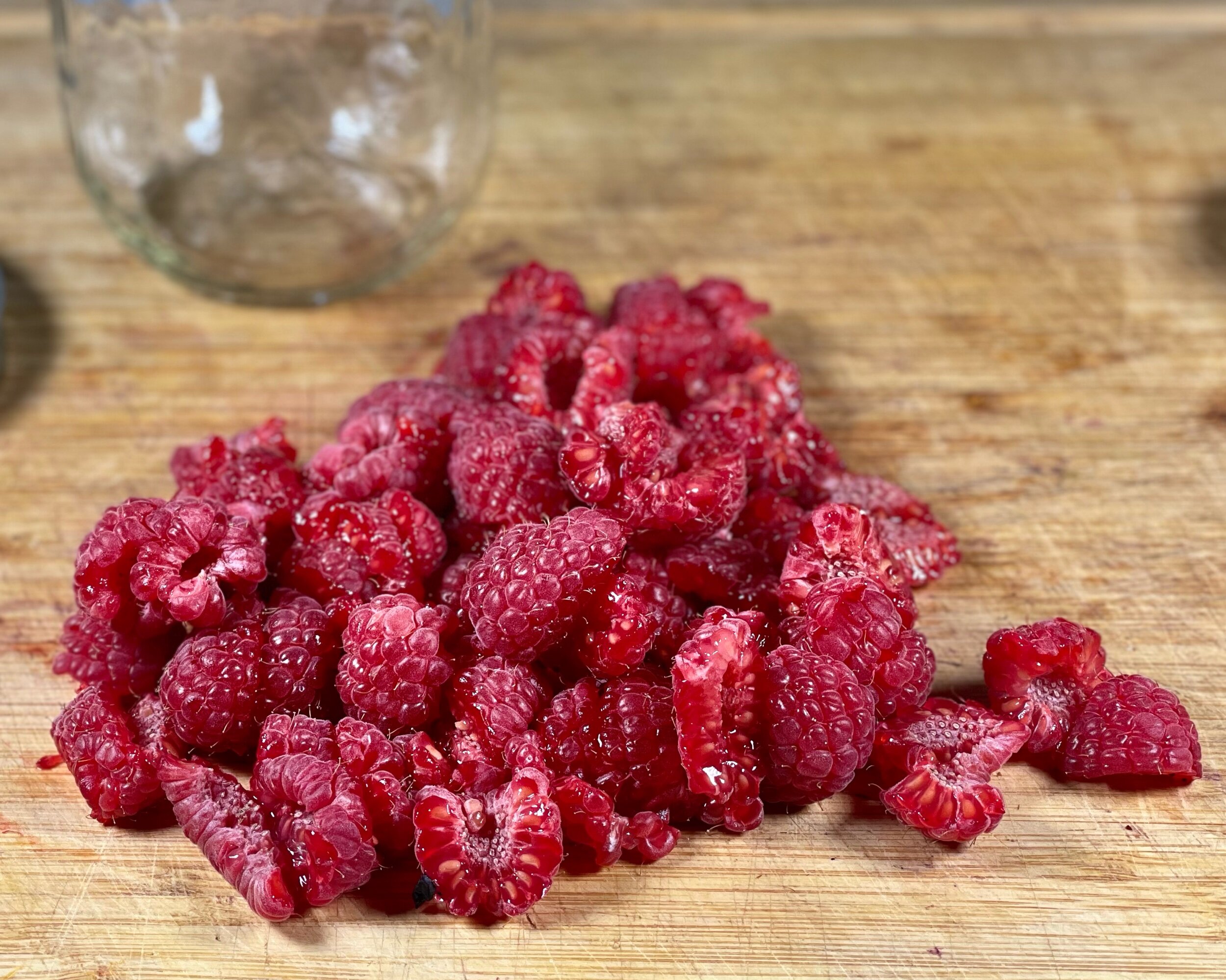  Pile of raspberries lightly chopped up on a cutting board. 