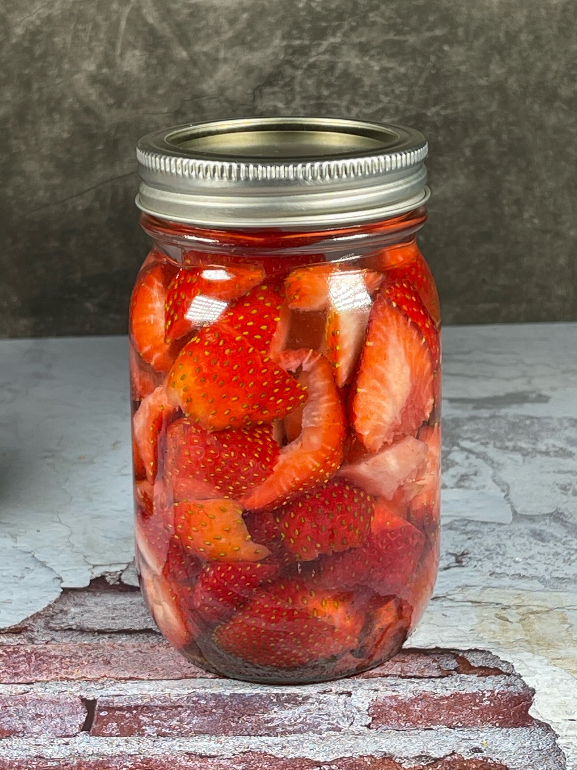  Red strawberries back in their jar with vodka filling it up and making sure all fruit is submerged. 