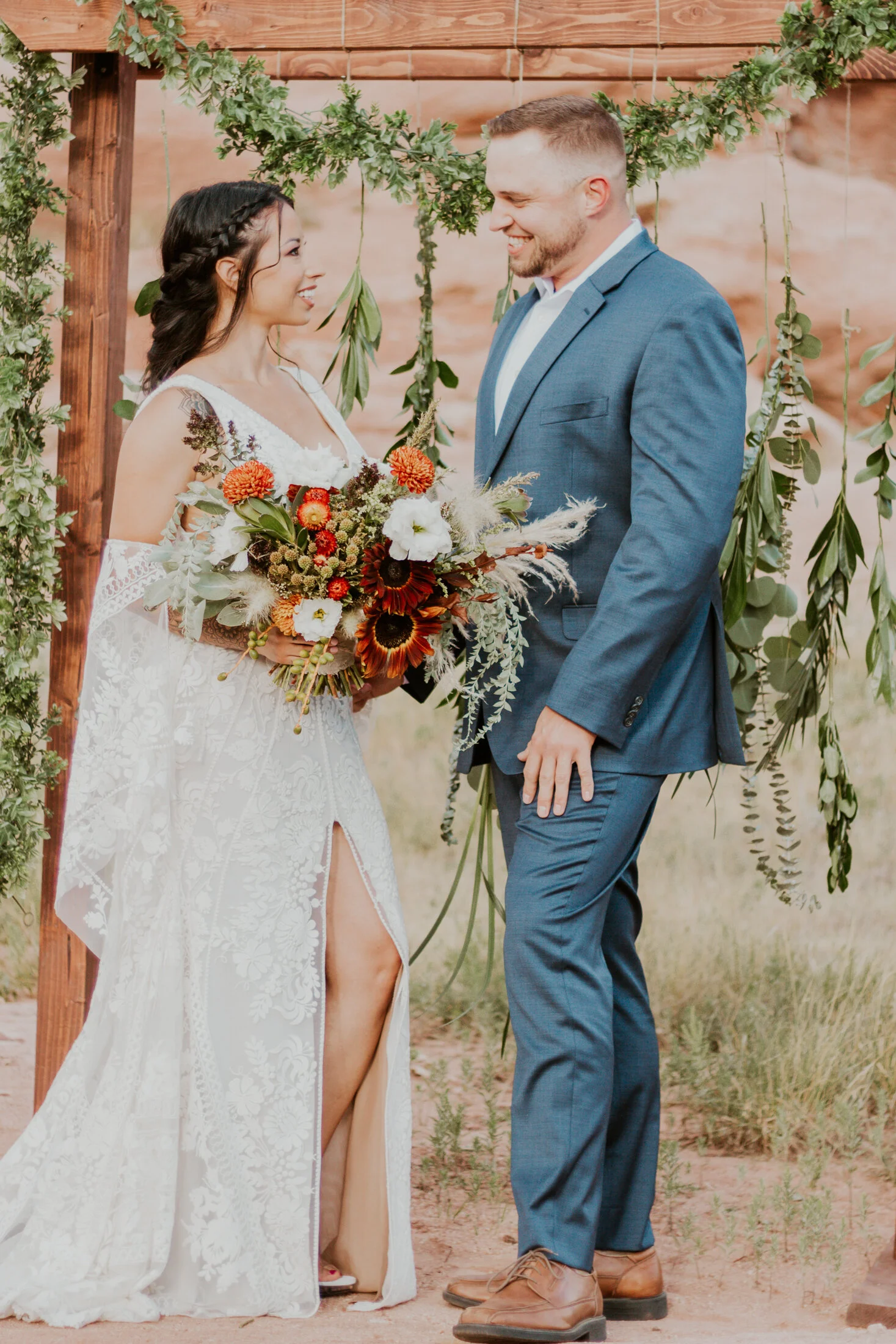  Denver, Colorado’s Dawn Louise Photography captures bohemian styled bride and groom celebrate beneath their wedding arch in Red Rocks, Colorado. Red rocks mountain elopement, mountain wedding ceremony, bohemian styled wedding dress with lace, bell s