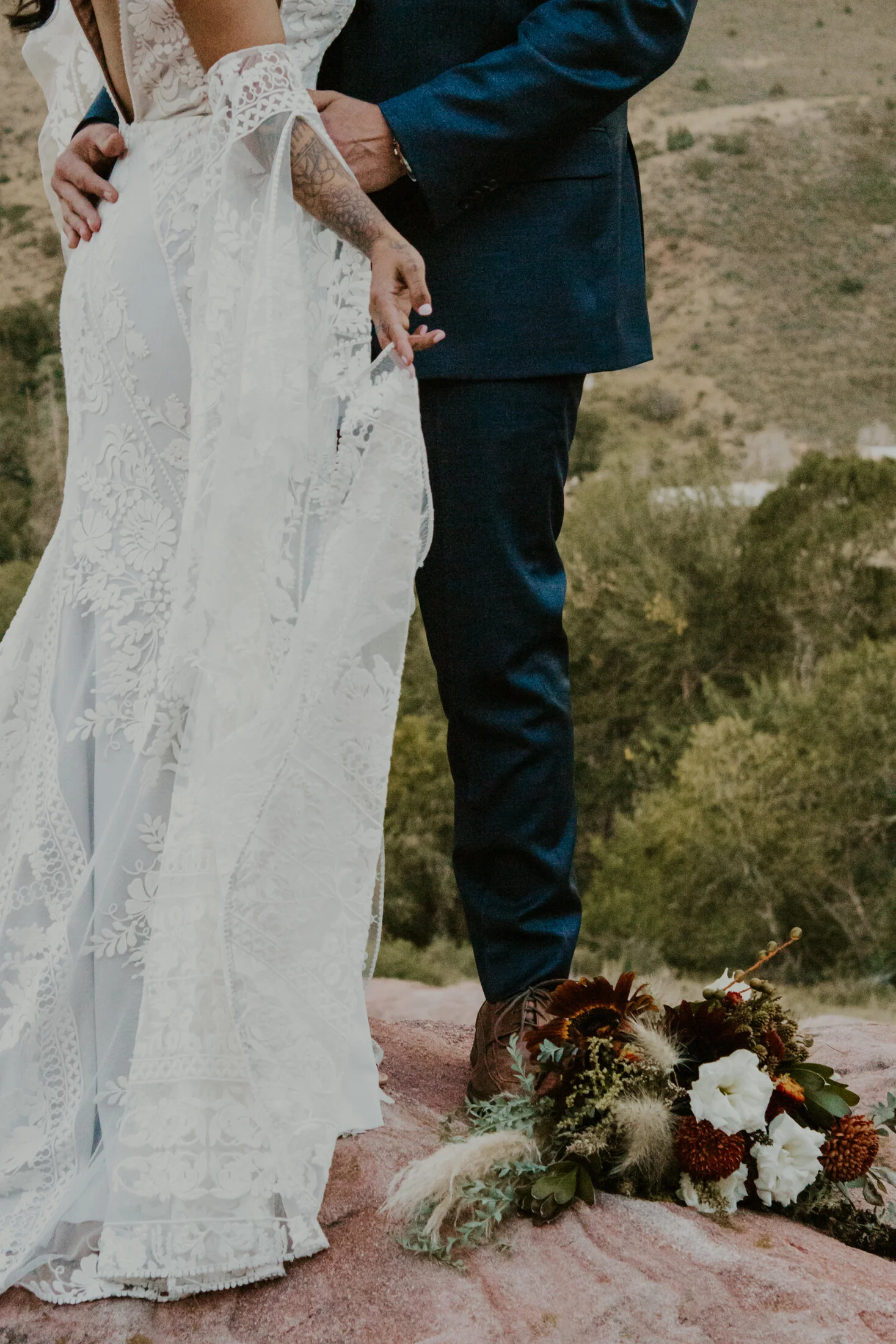  Posed on a peak at the Colorado Red Rocks, Dawn Louise Photography captures tender moment of bride and groom hugging. colorado red rocks mountain peak, colorado red rocks wedding, professional denver colorado wedding photographer, bohemian lace wedd
