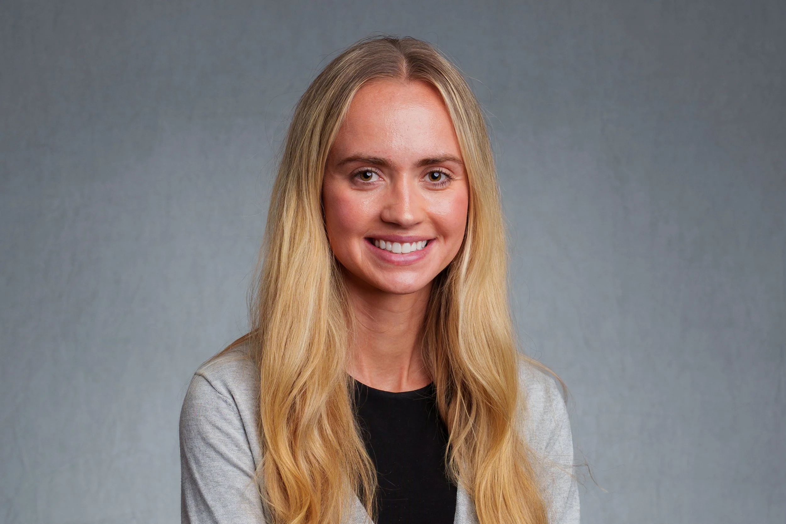 Close-up professional headshot of a smiling woman photographed against a neutral gray background in Scottsdale, Arizona