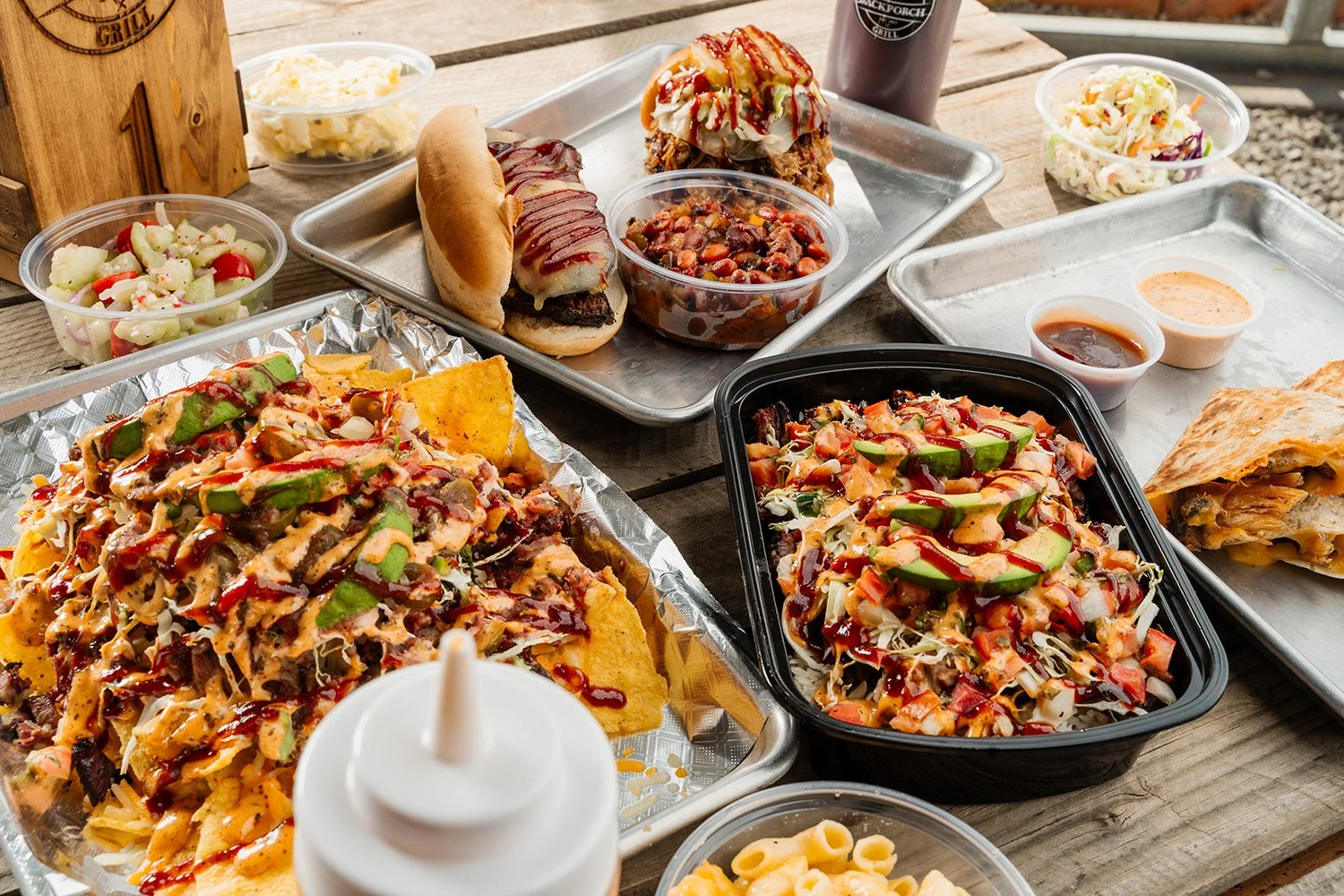 Assorted Tex-Mex food including tacos, nachos, salad, and sauces on a wooden table.