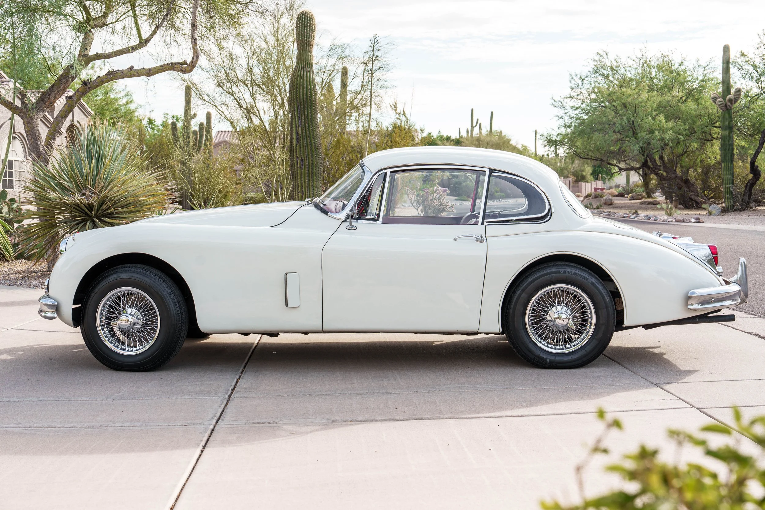 Driver-side profile of a white 1960 Jaguar XK150 Fixed Head Coupe