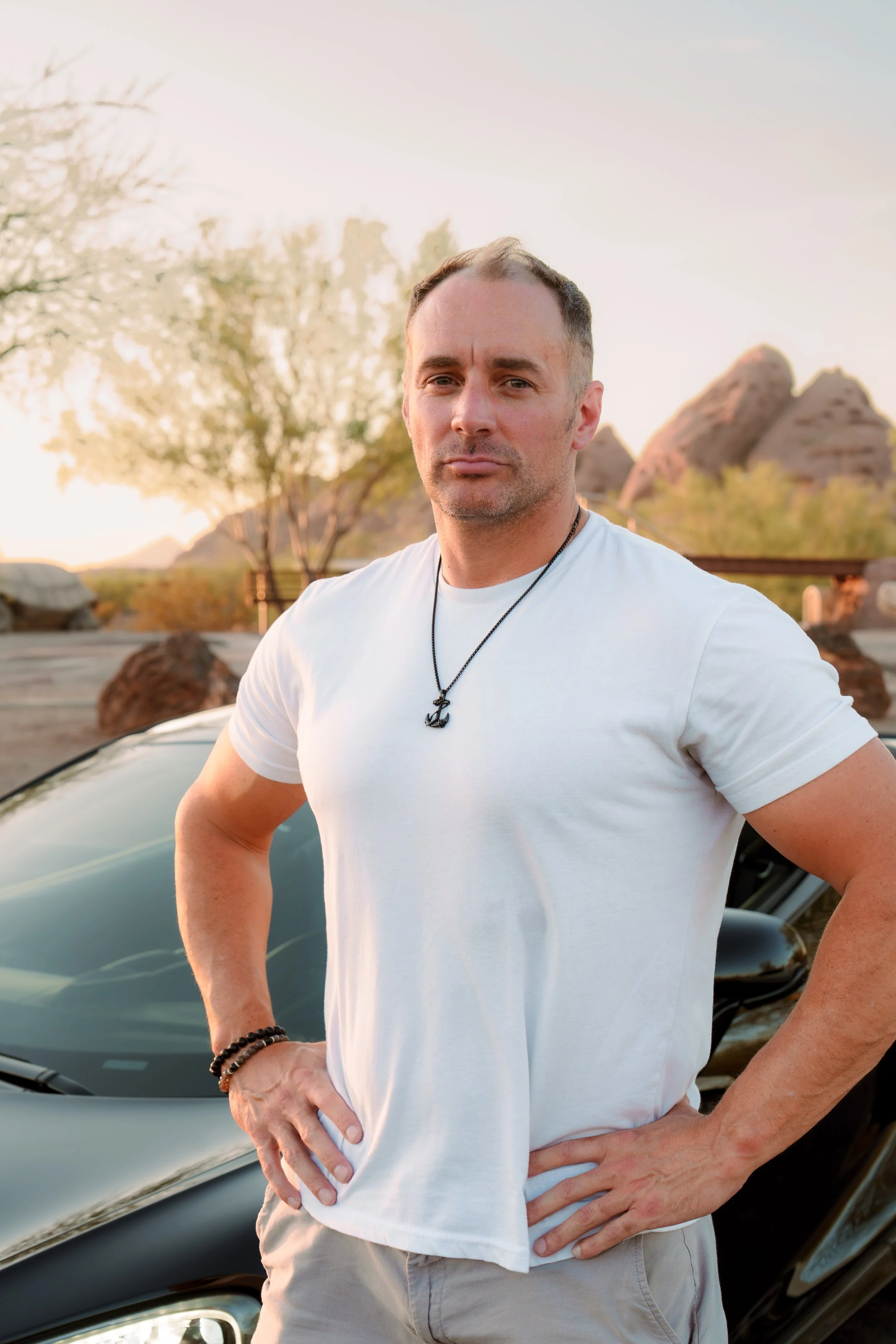 Professional male branding portrait beside a black McLaren at Papago Park